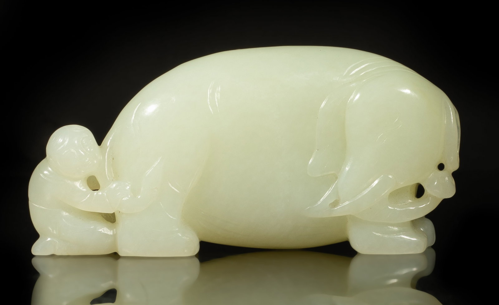 Chinese Russet White Jade Table Sculpture: Carved as a boy kneeling behind a chubby elephant, the elephant head turned backward looking at the boy, the stone of white hue with russet inclusions. Approx. 3.73*1.77*1 inch.