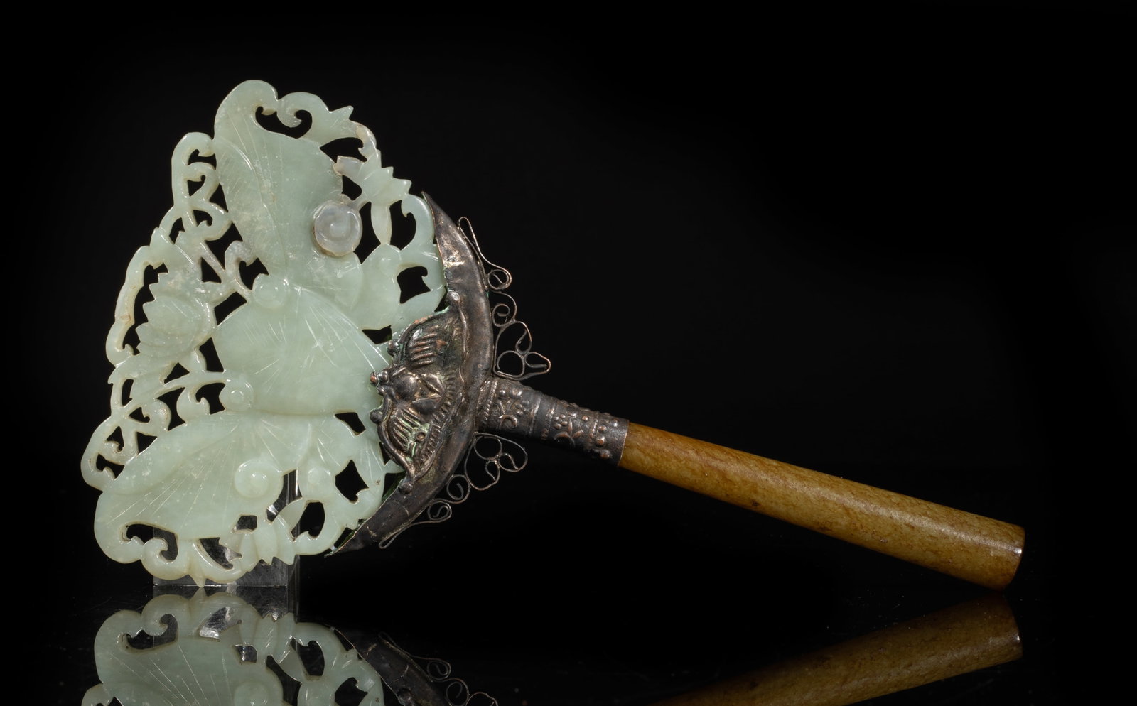 Chinese Export Jade Carved Butterfly: Carved in openwork with a butterfly flanked by flowers, the pale celadon stone with some cloudy inclusions, with a metal link and a russet jade handle. Approx. 6.7*3.7 inch (w/ handle). The Estate of