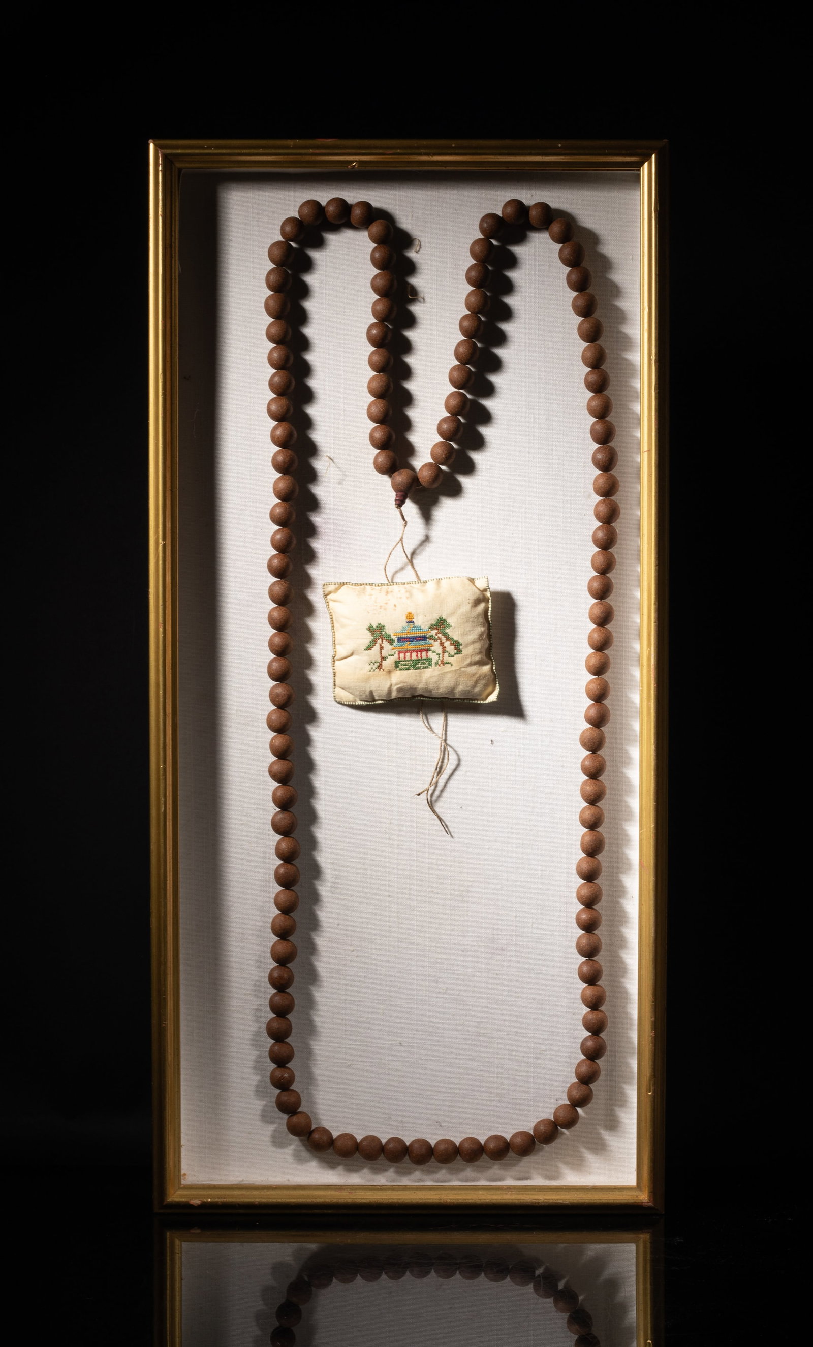 Long Chinese Mixed Agarwood Hexiang Prayer Beads: A long string of Chinese mixed agarwood hexiang prayer beads, with a sachet, fixed on a framed board. Approx. 25*12 inch (frame size).