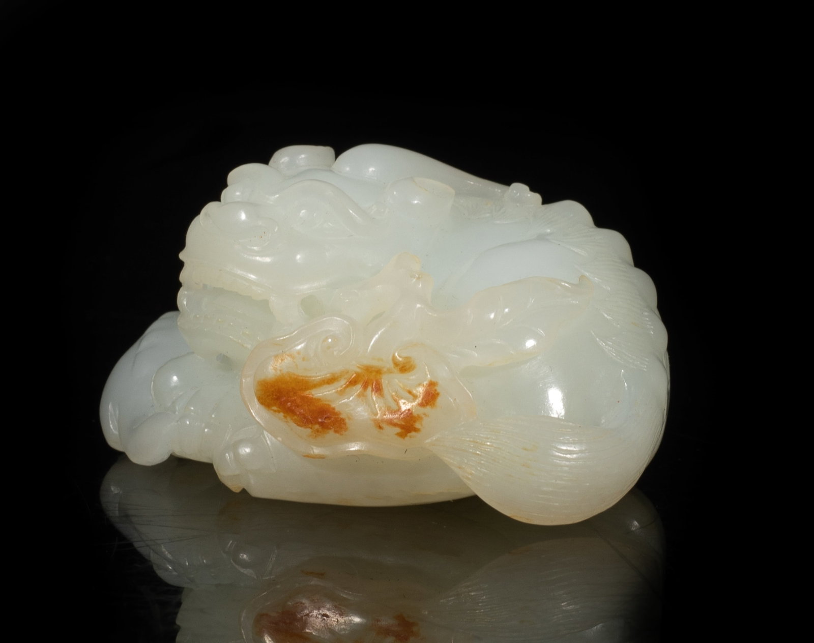 Chinese Russet White Jade Beast: The recumbent creature depicted recumbent in a relaxed position with head turned left, its teeth depicted clenching on a stem issuing lingzhi, its defined body form with a vivid spine running down