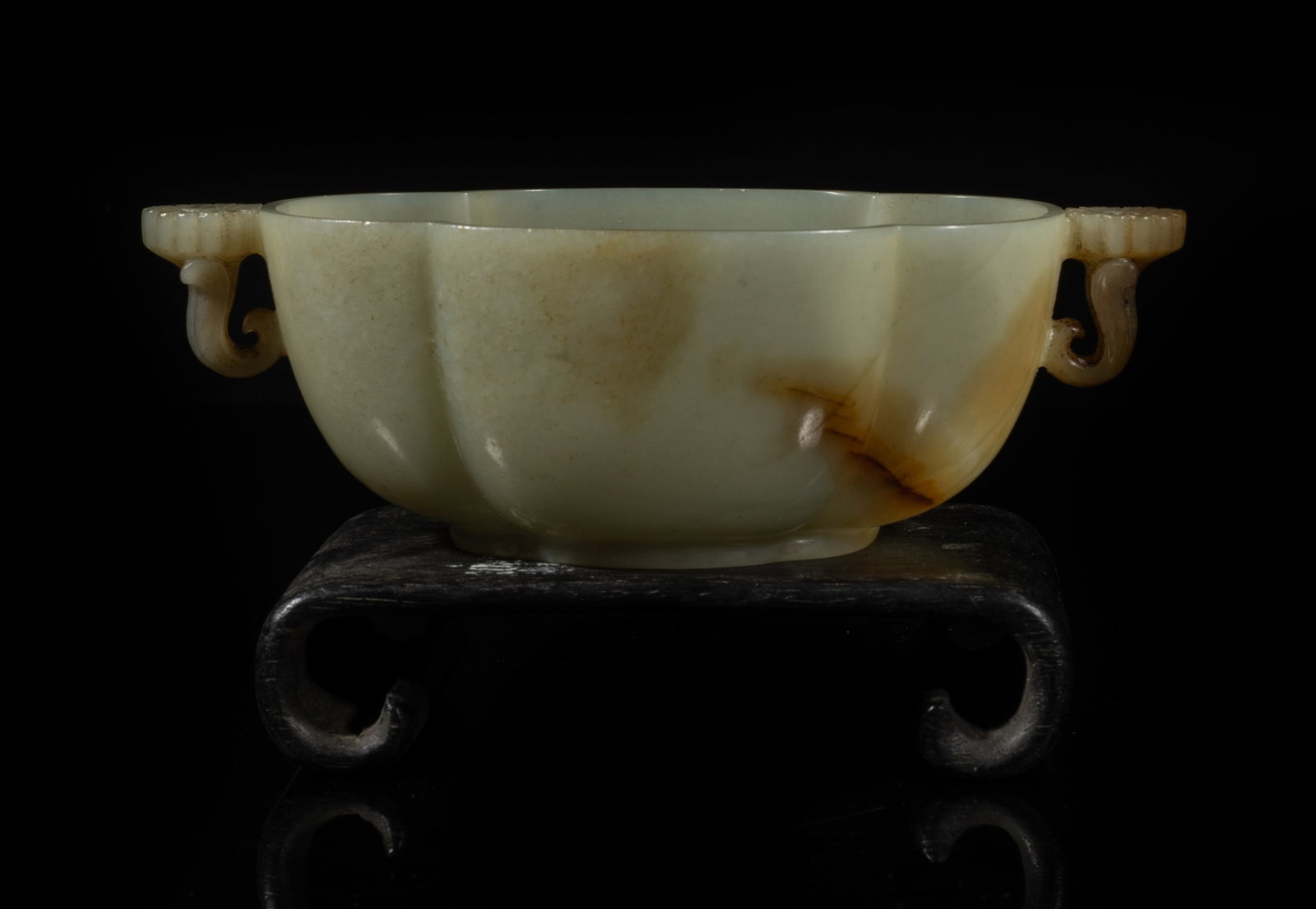 Estate Chinese Russet Jade Washer on Stand: The jade washer of ruyi head section, carved with two flowers at the narrow sides forming as handles, the stone of pale celadon tone with russet inclusions, with wood stand. Approx. 5.6*3.1*1.8 inch