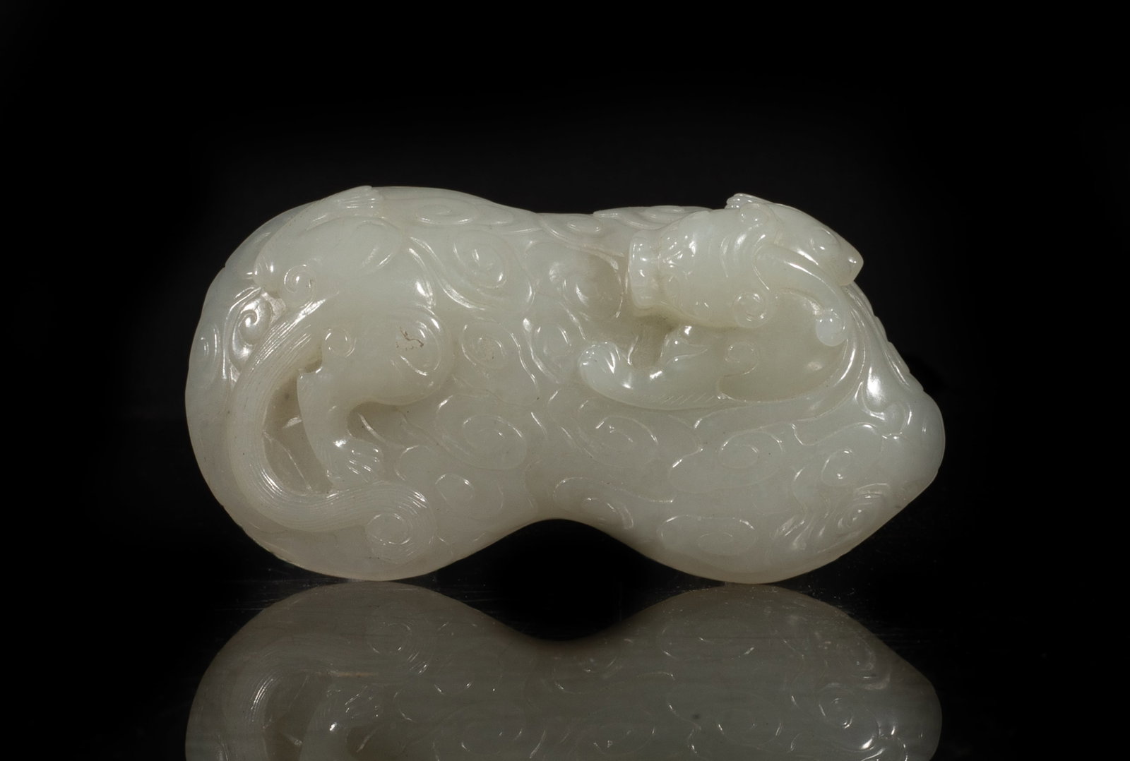 Chinese White Jade Carved Belt Buckle: Of peanut shape, one side carved with a beast through scrolling clouds, the underside with two circular knobs. Approx. 3.07*1.64 inch. he Estate of the Consignment Store Closed Sale, Palm Springs.