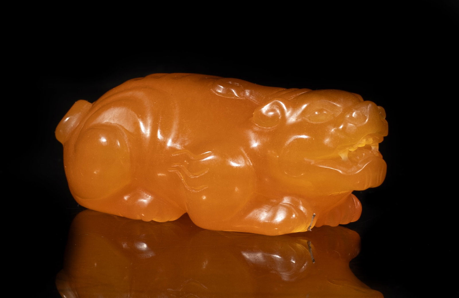 Vintage Chinese Tianhuang Beast Sculpture: The honey-brown stone carved as a recumbent single-horned beast, its four legs tucked under the body, the muscular body ending with a bifurcated tail. Approx. 3.15*1.6*1.1 inch.