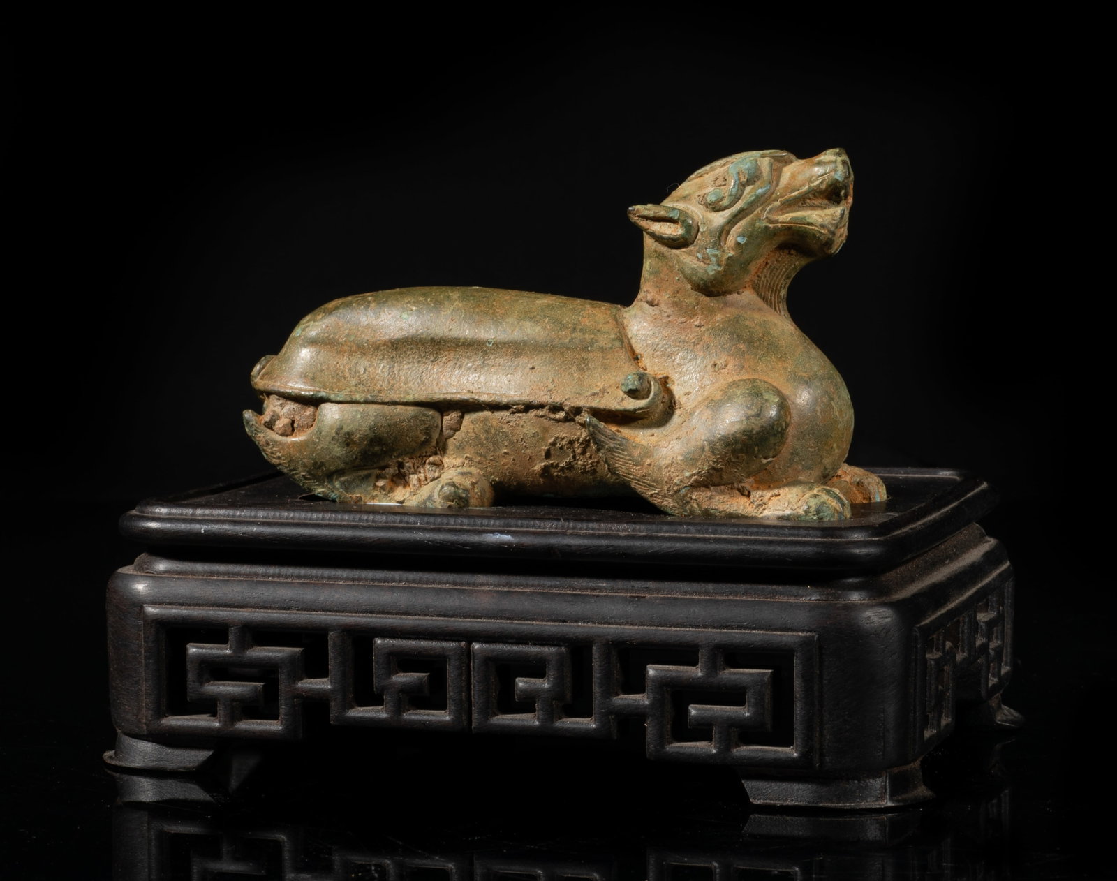 Chinese Bronze Beast Sculpture w/ Wood Base: Cast in the form of a beast, raised on four strong limbs ending in powerful paws, the elongated body ending in a scrolled tail, with a wood base. Approx. 5.2*3.9*3.6 inch (w/ stand). The Estate of the