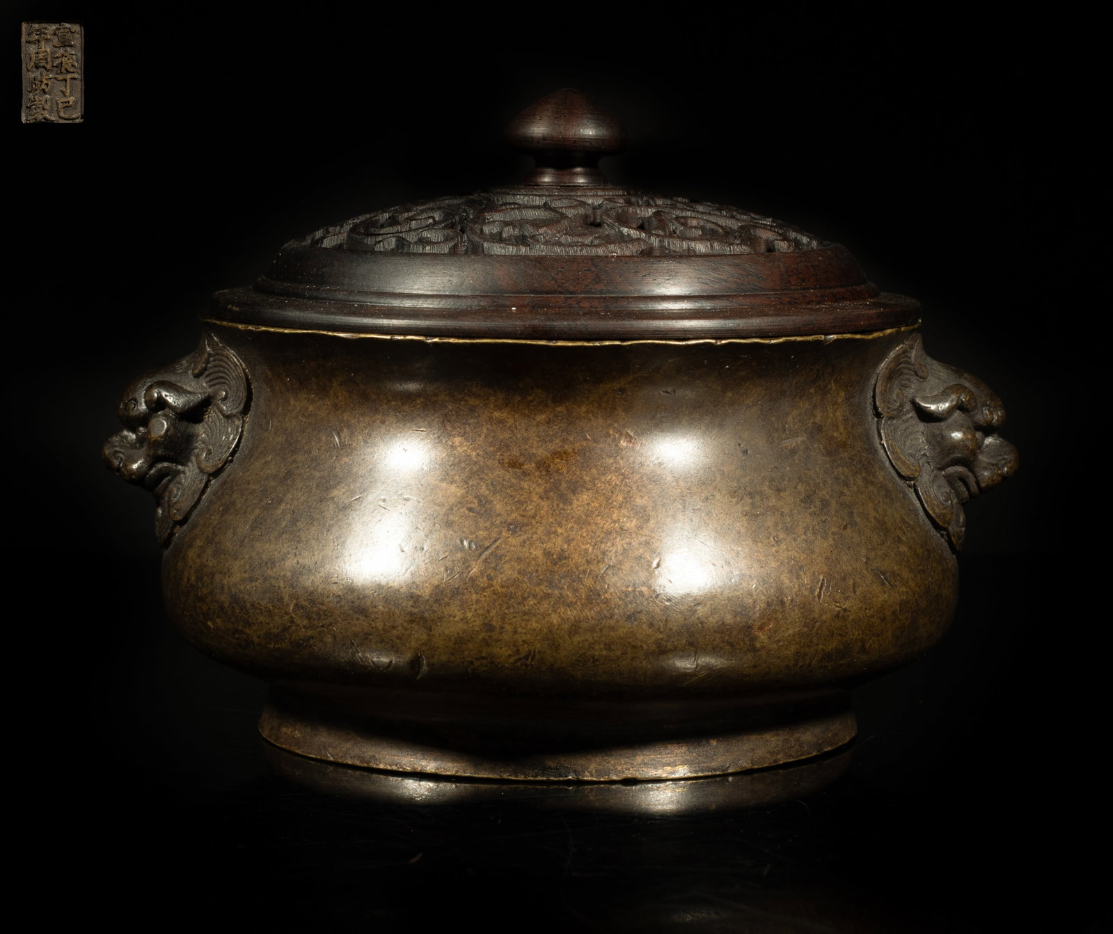 Chinese Bronze Censer w/ Wood Cover: Of compressed form rising from a short foot to a spreading mouth, cast with two raised beast masks forming as handles, the bottom with an eight-character mark, with an openwork wood cover. Approx. 5.2