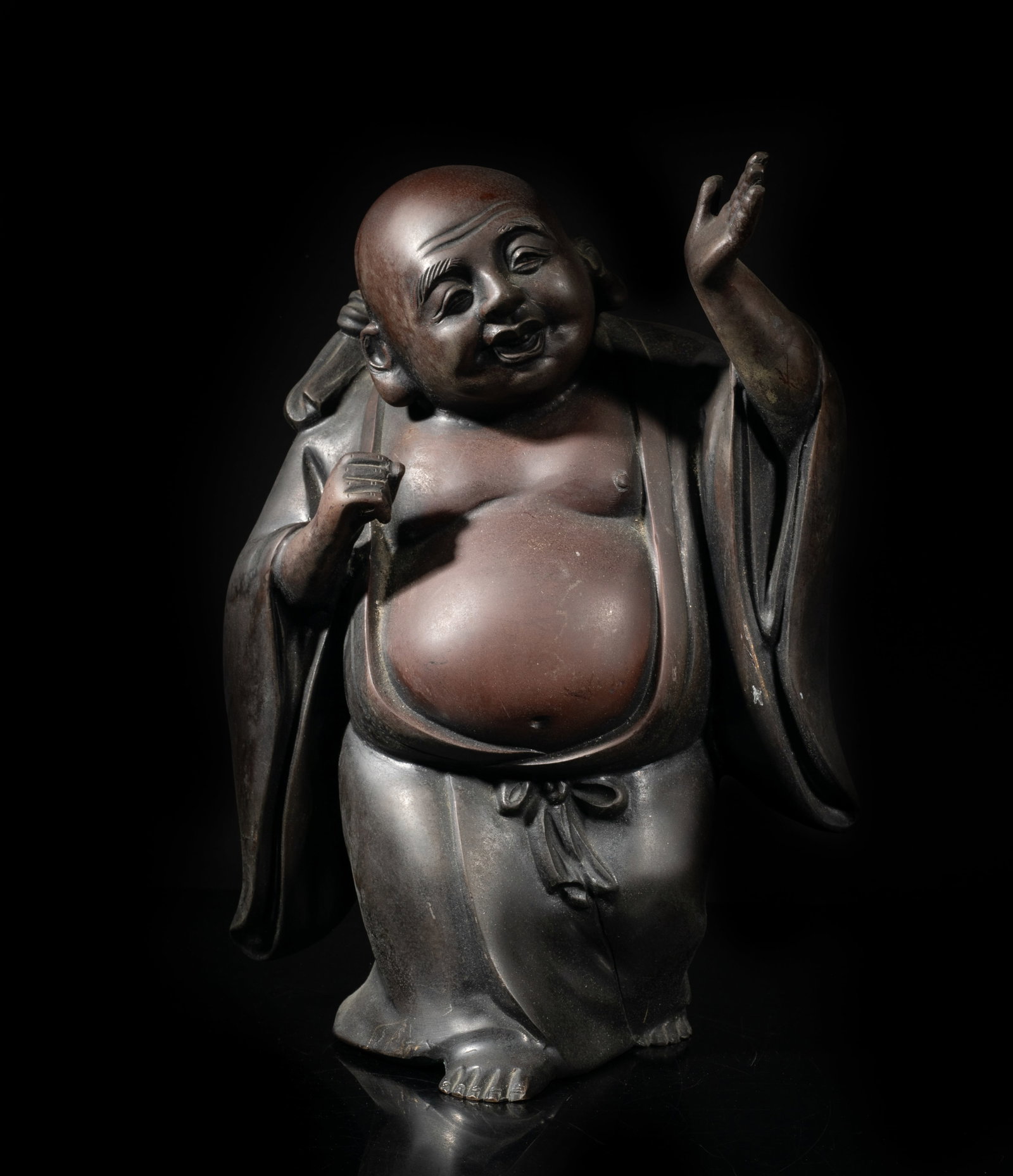 Japanese Meiji Bronze Sculpture of Buddha: Cast as a laughing Buddha wearing a long loose-fitting robe open at the chest, holding a bundle on the back. Approx. 11*8*5.6 inch.