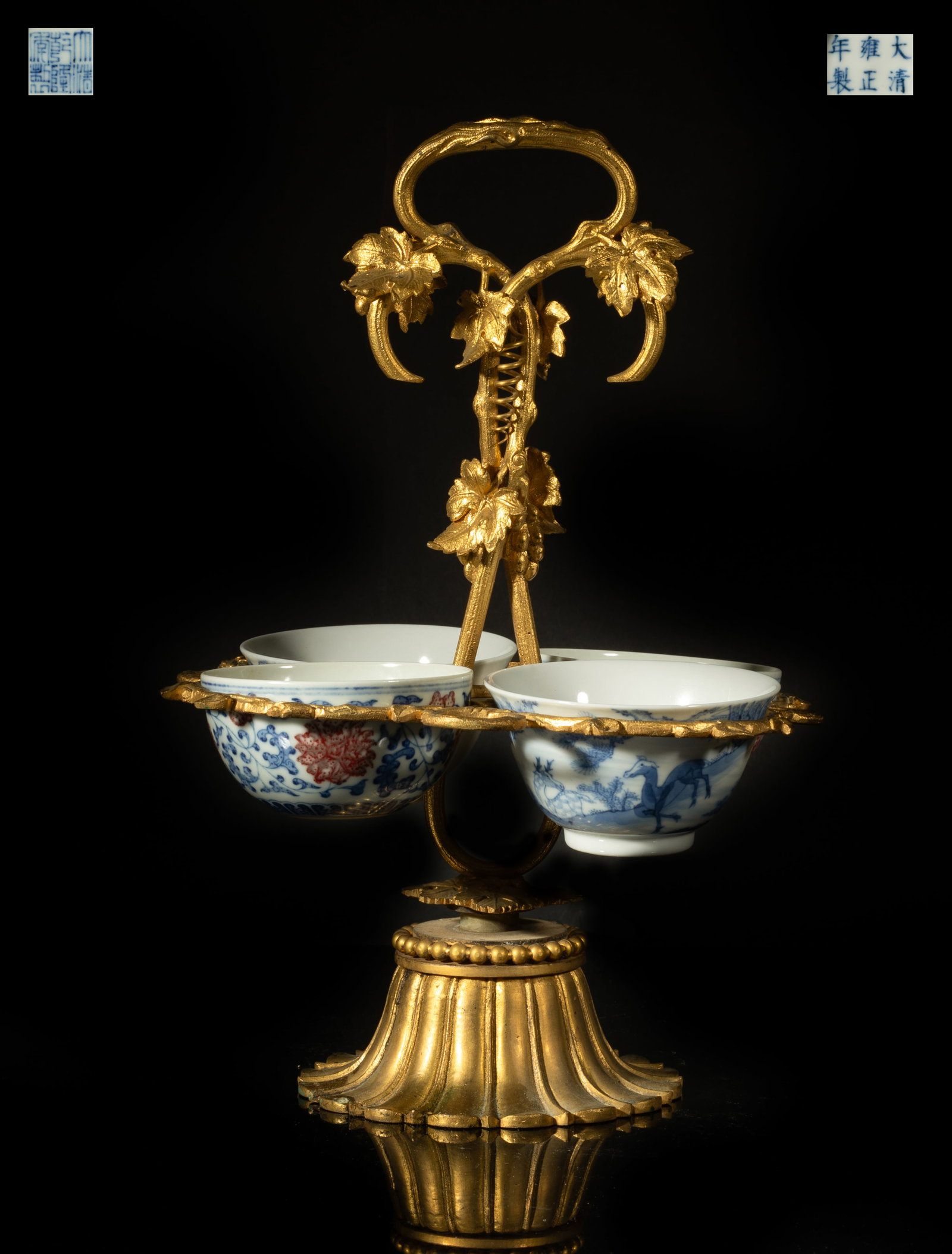 Chinese Porcelain Tea Cups w/ Gold Filled Stand: Two cups exterior painted in blue and copper red with lotus sprays above a band of petals, the other two cups exterior painted with deer in landscape, each cup bottom with a six-character mark, with