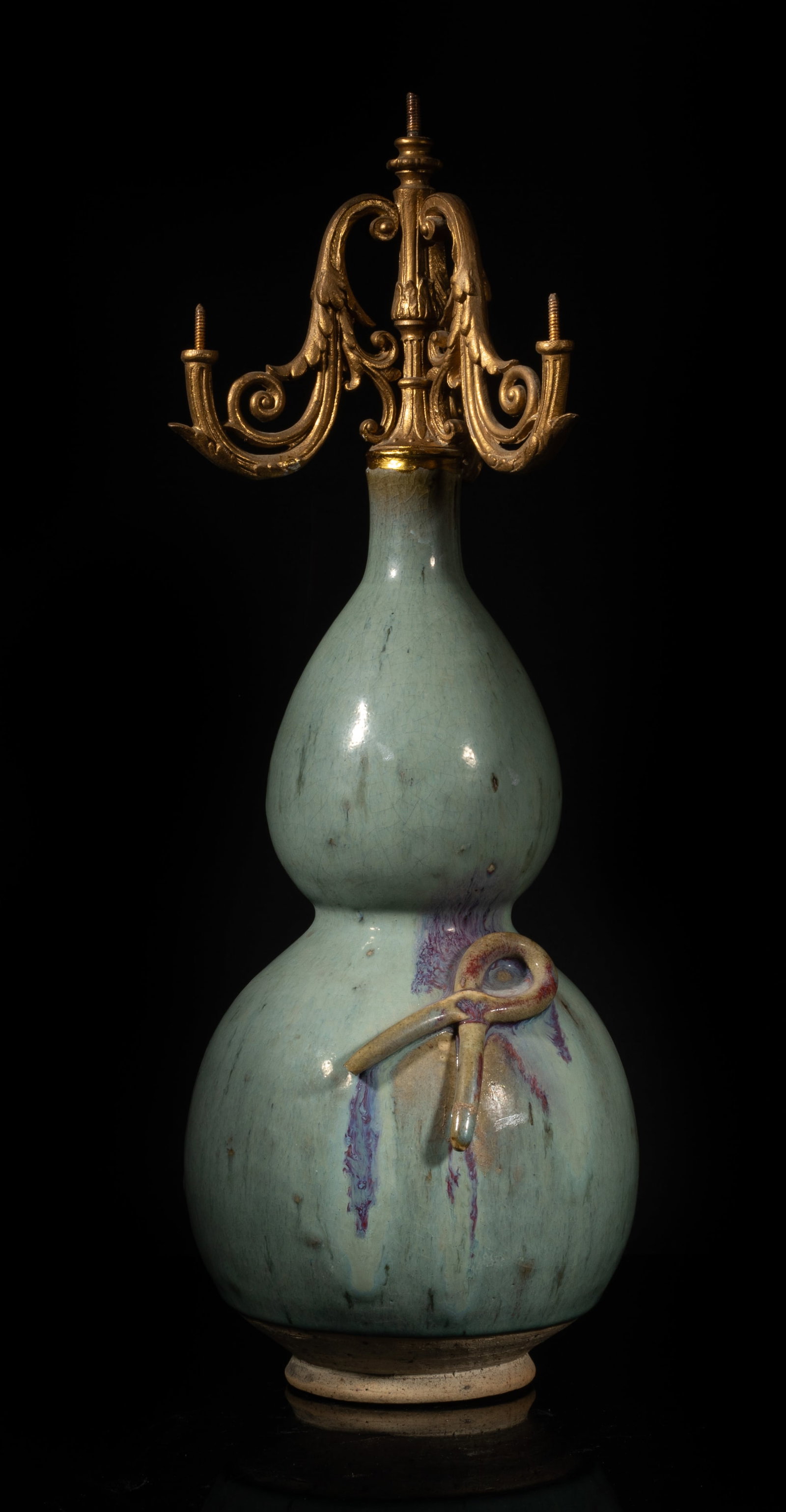 Chinese Jun Ware Porcelain Gourd Vase Candlestick: The porcelain vase of double gourd form, applied with crackled and mottled pale blue-gray glaze with purple splashes, decorated with a raised knot, surmounted with a metal cast candelabra. Approx.
