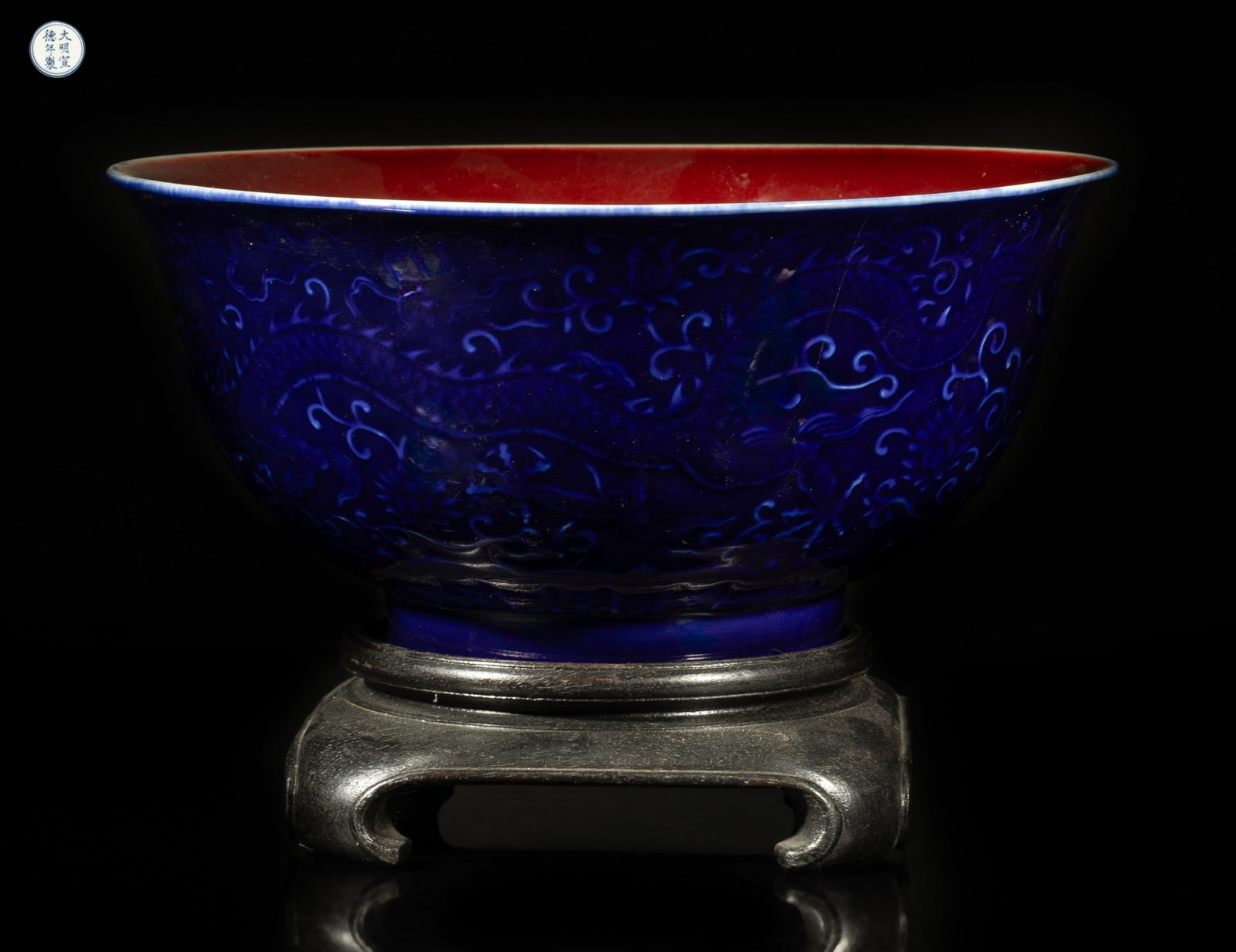 Large Chinese Export Porcelain Bowl w/ Base: The large bowl interior covered with rich red glaze, the exterior carved in low relief with two dragons sinuous among lotus scrolls above a band of petals, covered with dark blue glaze, the bottom