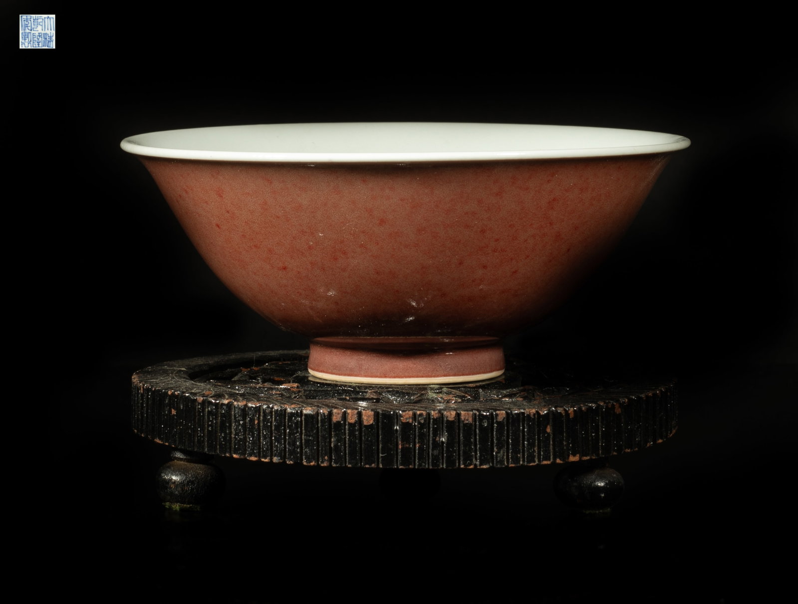 Chinese Red Glazed Porcelain Bowl w/ Wood Base: The bowl exterior covered with mottled red glaze, the bottom with a six-character mark, with a wood base carved in openwork with leafy stems. Approx. 5.2*2.1 inch (w/o stand). The Estate of the Store 