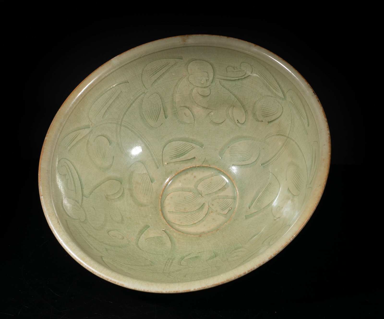 Large Chinese Yaochou Porcelain Bowl: The bowl interior carved in low relief with boys and stylized flowers, the exterior with radiating lines, overall covered with crackled celadon glaze. Approx. 7.5*3.4 inch.