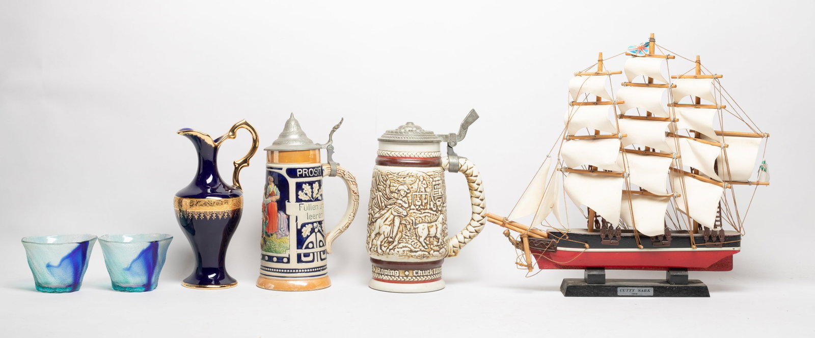 Vintage Sailboat, Porcelains, Glass Wares: Including three porcelain pitchers, two glass cups, and a sailboat sculpture. Approx. 13.5*13*2.5 inch (boat size).