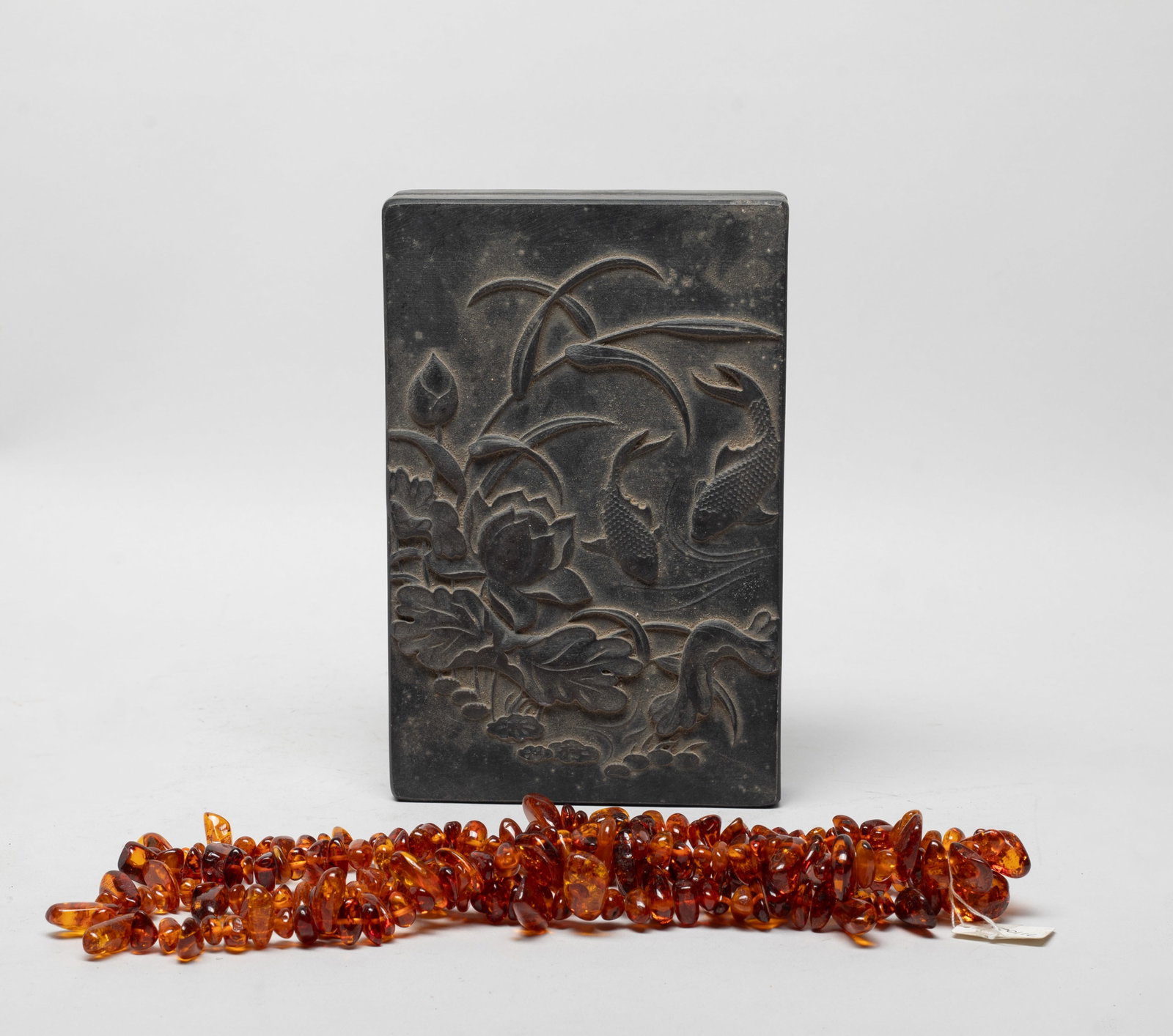 Estate Chinese Ink Stone & Amber Necklace: Including a ink stone of rectangular shape, with a case carved with lotus and fish, and a long amber nugget bead necklace. Approx. 38 inch L (necklace size).