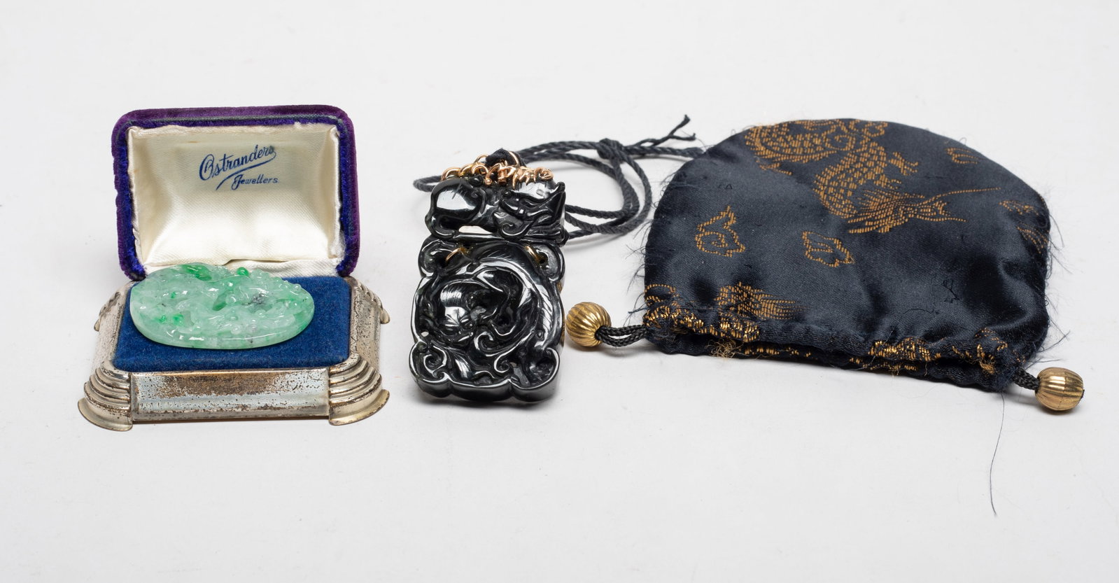 Chinese Jade Jadeite, Gold Pendants: One pendant carved on both sides with a beast recumbent over another beast, the gold bail with no mark, with a cloth bag, the other pendant carved with a flower tree, with box. Approx. 1.43*2.27 inch