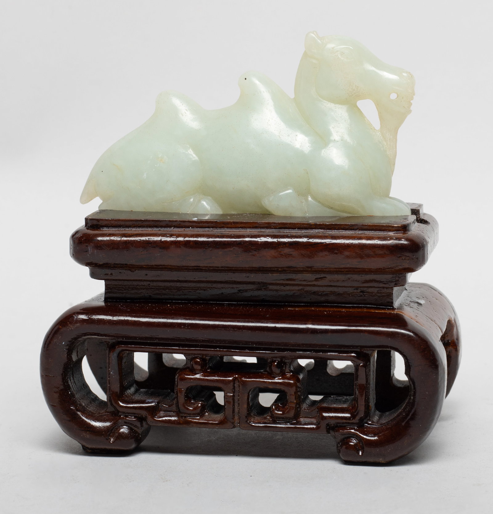 Estate Chinese Jade Sculpture on Wood Base: Carved as a camel in recumbent pose, drilled through the mouth, affixed to a stand. Approx. 4*3.8*2.2 inch (w/ stand).