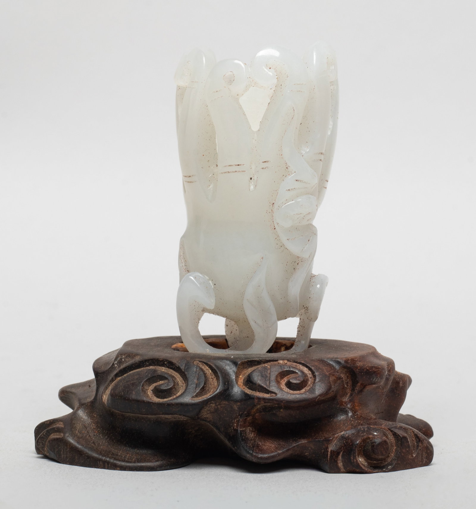 Chinese White Jade Buddha Hand on Stand: Naturalistically carved as a buddha hand citron from a short stem issuing an attendant lingzhi, with a bat on the fruit, affixed to a wood stand. Approx. 3.05*1.8*3.2 inch (w/ stand).