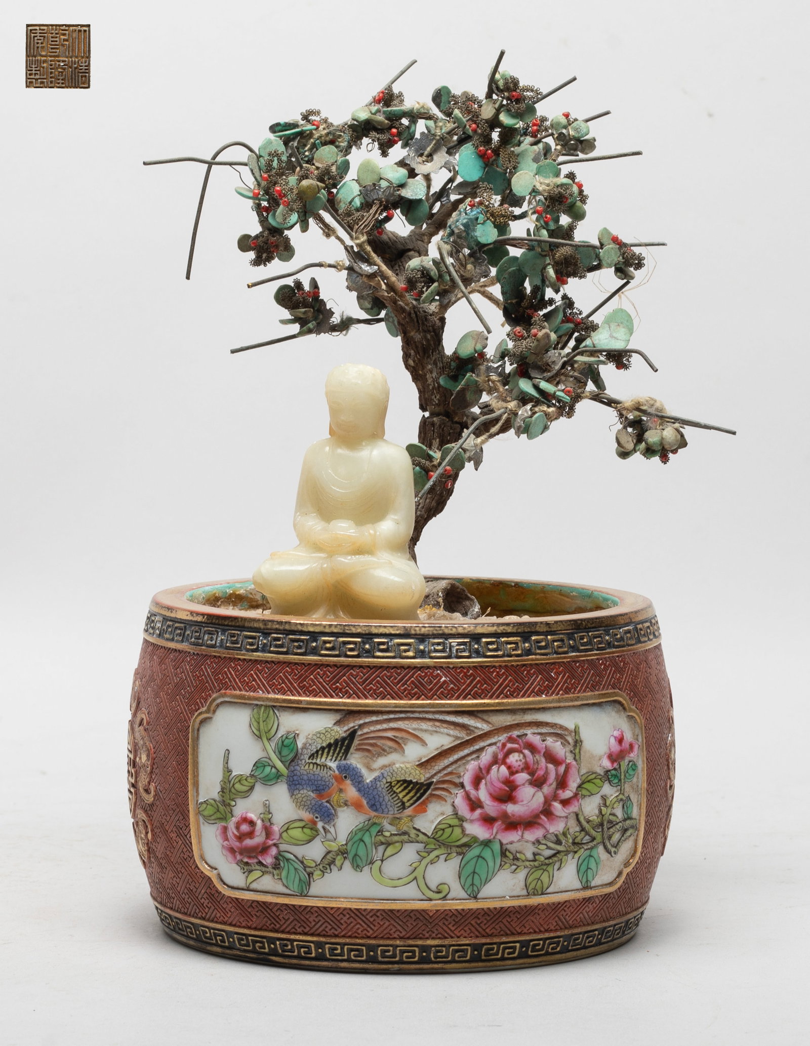 Rare Chinese Jade, Stone, Porcelain Bonsai: Carved with a jade Buddha seated under a stone flower tree, the hands holding an elm bowl, the porcelain pot decorated with two panels enclosing lotus and birds or peony and birds, against red glazed 
