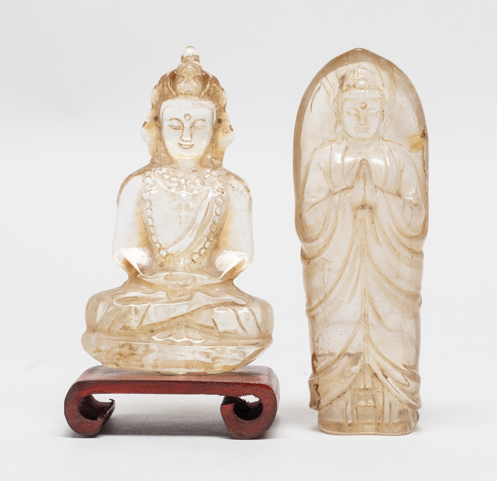 Two Chinese Export Crystal Sculptures of Buddha: One Buddha carved standing and wearing a long robe, the hands in namaskara mudra, the other seated Buddha with hands in dhyana mudra, with a stand. Approx. 3.65*1.3*0.9 inch (larger). The Estate of