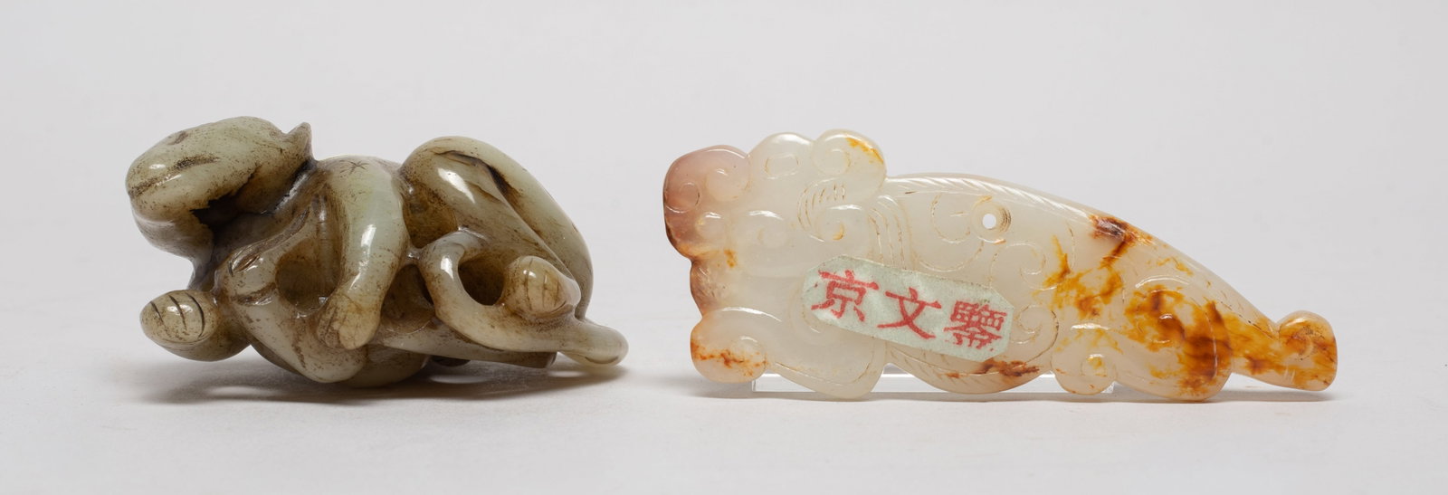 Two Chinese Jade Carved Pendants: One carved as a recumbent monkey holding a peach under its body, the other flat pendant worked of archaistic beast form with its head turned backward. Approx. 2.77*2.1*1.3 inch (larger). The Estate