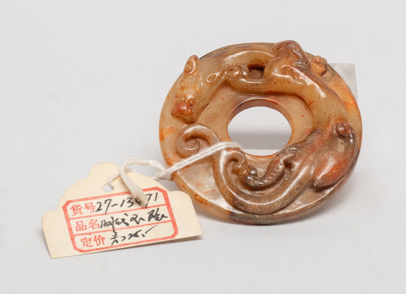 Chinese Russet Jade Pendant of Bi: Of circular shape, one side carved in high relief with a sinuous beast, the reverse carved with raised bosses. Approx. 2.3 inch D. The Estate of the Store Moving Sale. Palm Springs. CA. 2025.