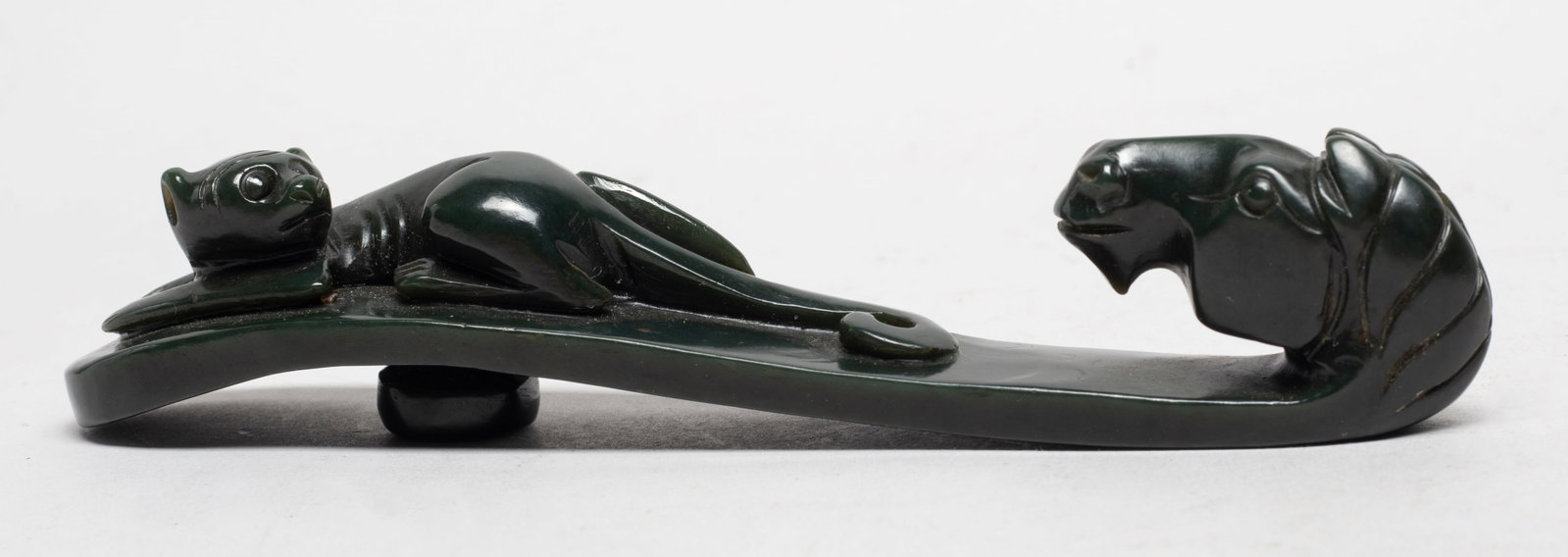 Chinese Spinach Jade Belt Buckle: The terminal carved in the form of a well-detailed horse head, with a monkey recumbent covering the length of the curved shaft, the underside with a flat oval button. Approx. 6.2*1.2*1.2 inch.