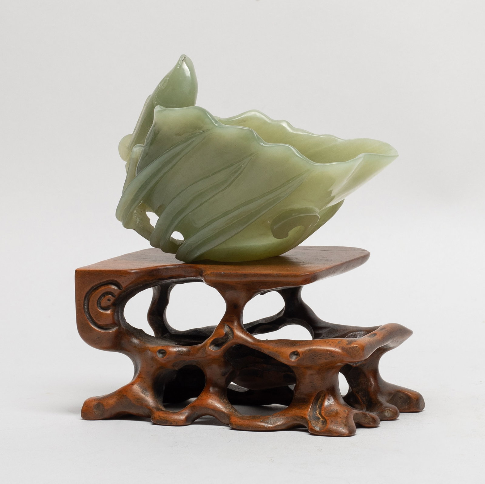 Chinese Jade Carved Cup w/ Wood Base: Finely worked in the form of a folded leaf, the exterior with a further leaves issuing from curved undercut stems forming a foot, a fish at the side forming a handle, with stand. Approx. 3.6*2.3*2.7