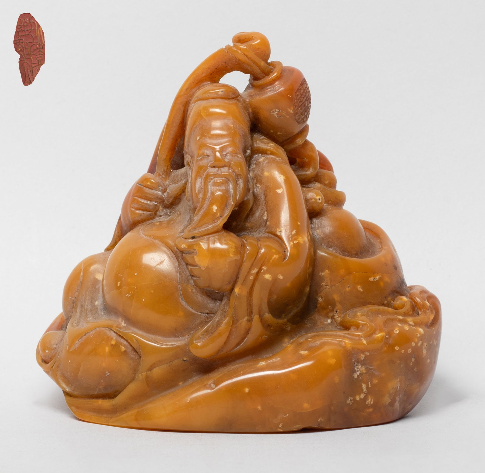 Chinese Rich Yellow Shoushan Stone Sculpture: Carved as an old man lying among ingots and coins. Approx. 3.8*3.6*2.1 inch.
