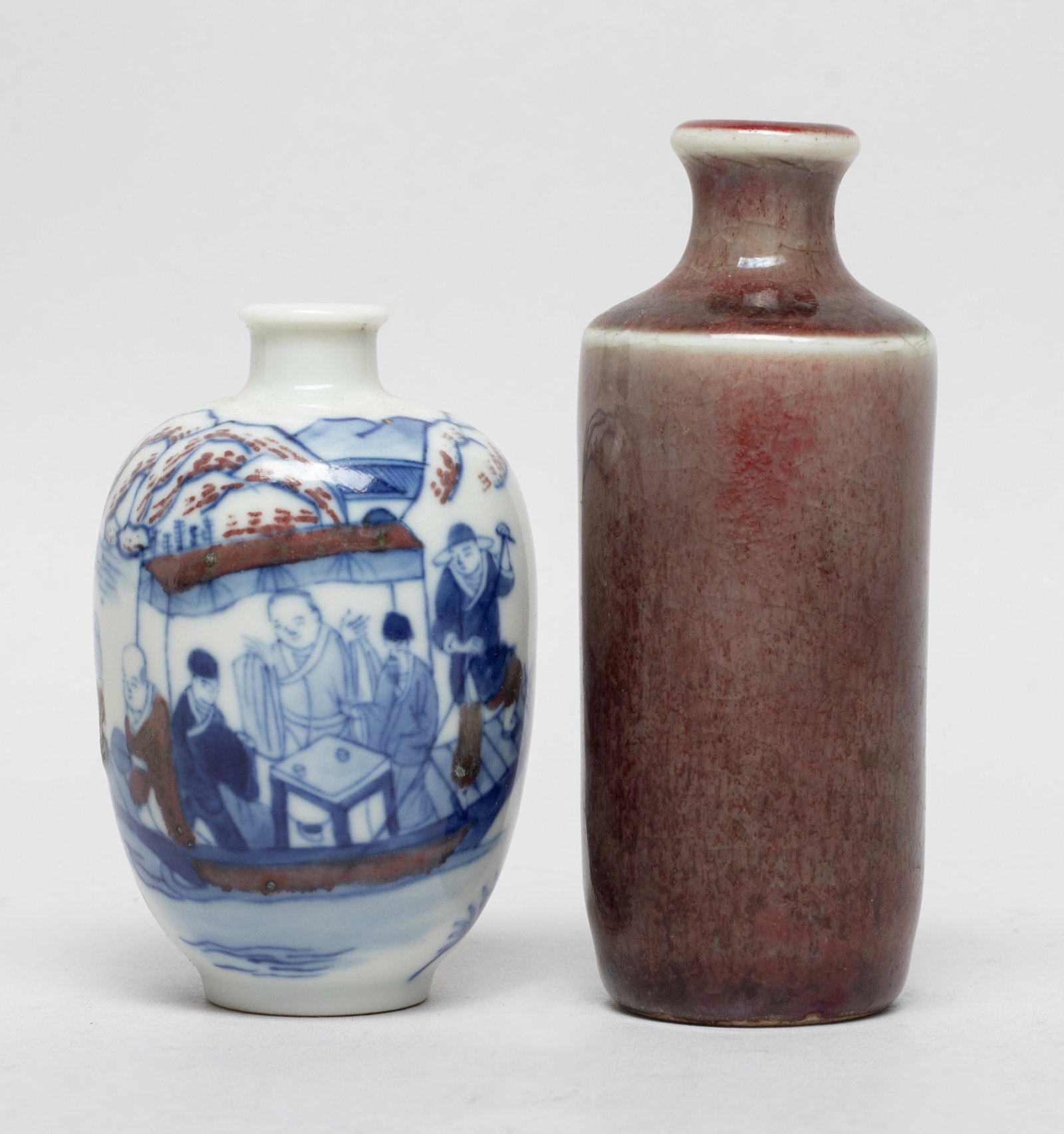 Two Chinese Porcelain Snuff Bottles: One snuff bottle of cylindrical shape with a waisted neck, the exterior covered with crackled and mottled dark-red glaze, the other of ovoid shape, the exterior painted with landscape scene, the