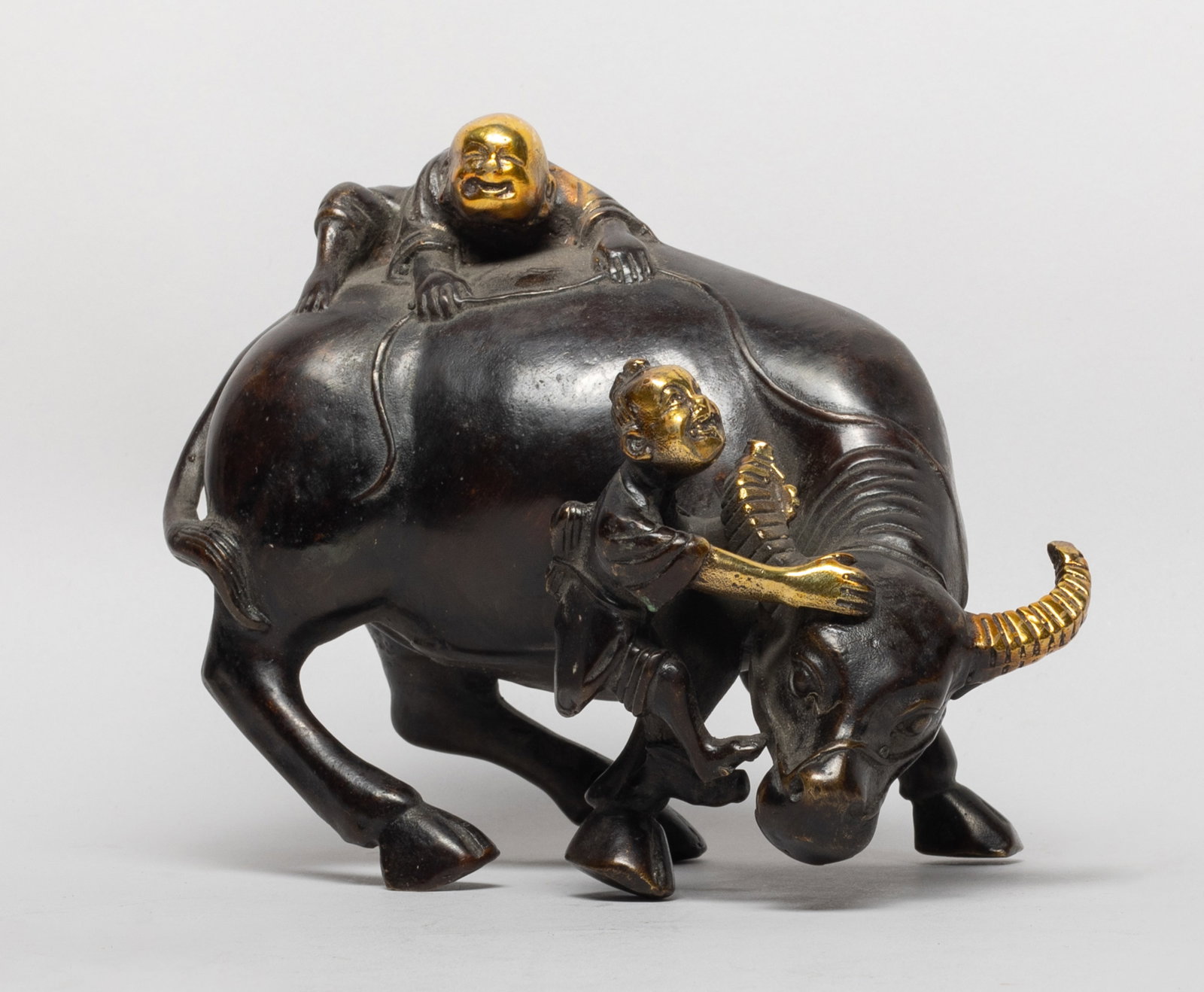 Vtg. Chinese Bronze Table Sculpture: Moulded as a buffalo with its head drooped and turned to right, a boy clambering on its head and another boy on the haunch . Approx. 6.4*5*3.8 inch. The Estate of the Judy & Mark. Los Angeles. 2020.