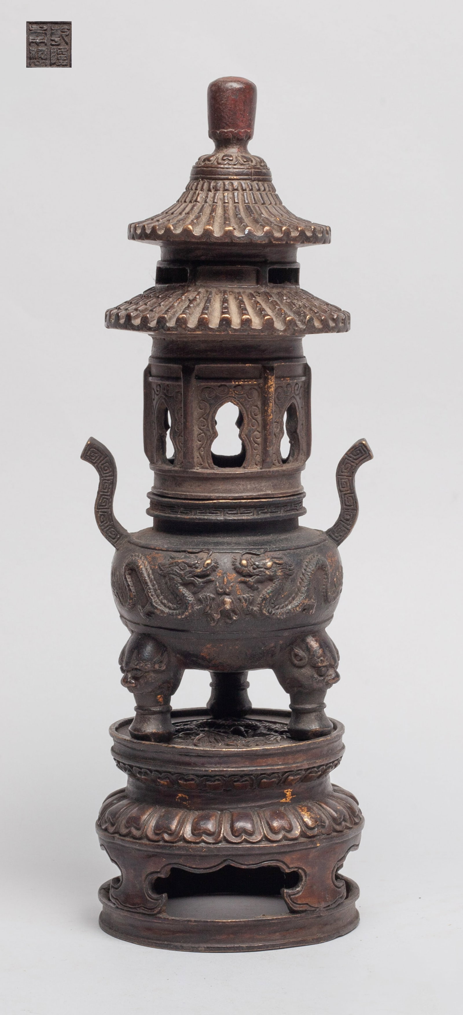Collectible Chinese Bronze Censer: The censer body cast with pair of dragons chasing flaming 'pearls', set with two handles and three legs, the stand top cast with similar dragon pattern, the cover molded in pagoda form. Approx.
