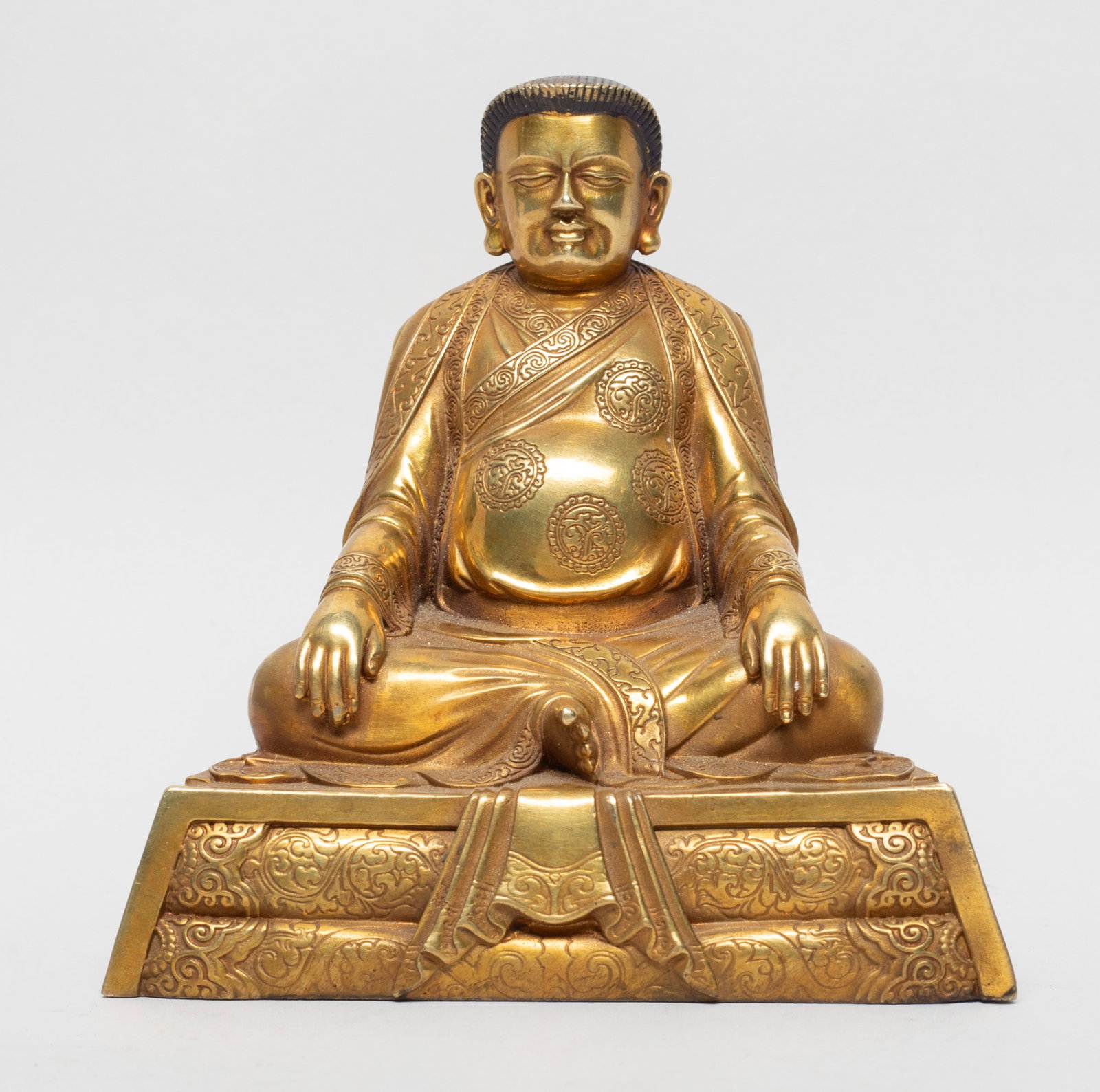 Chinese Sino-Tibetan Gold on Bronze Buddha: The seated Buddha wearing a loose-fitting robe, the hands resting on knees, the bottom marked with four characters and a Buddhist symbol. Approx. 4.2*4*2.5 inch.
