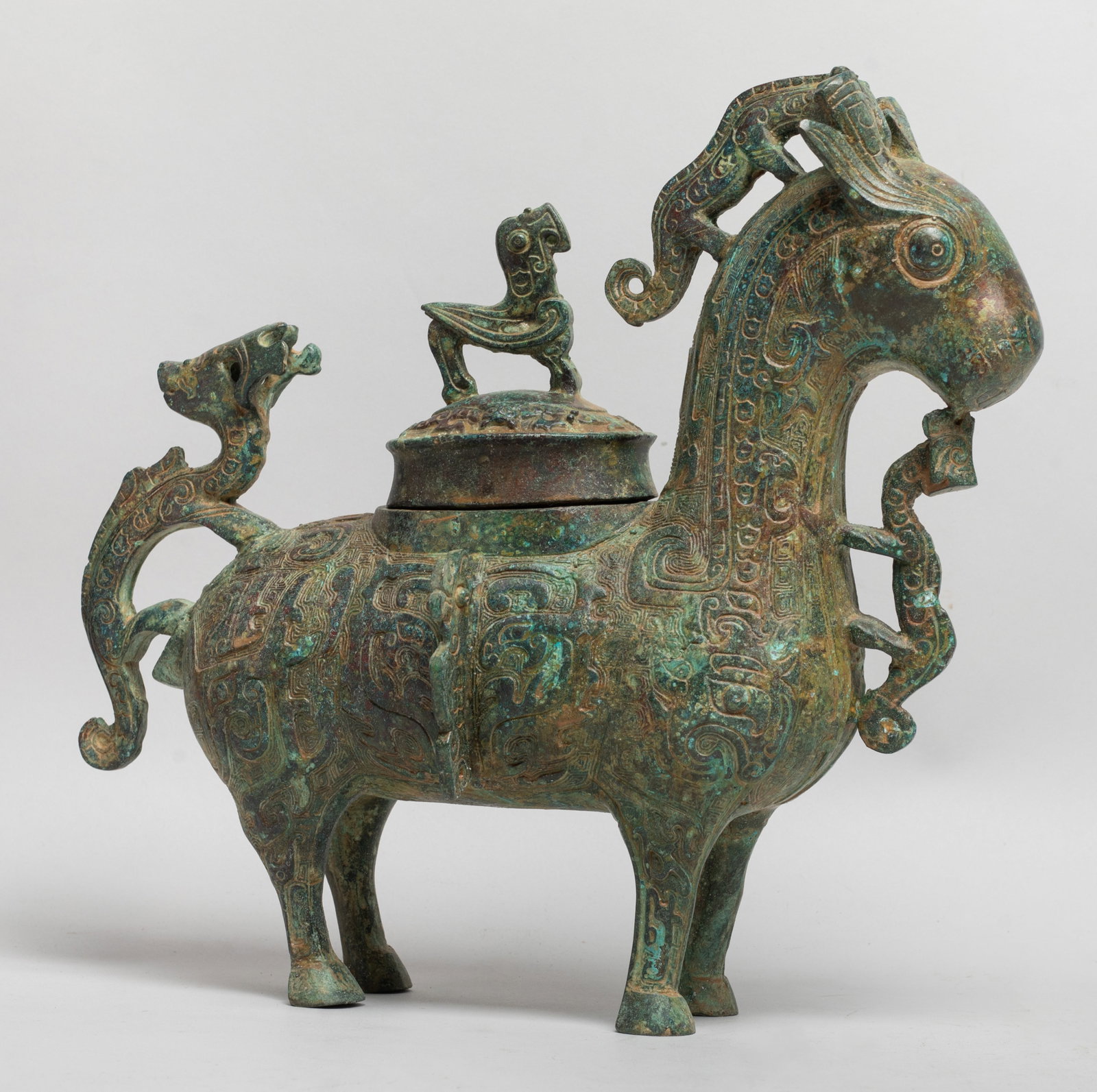 Chinese Bronze Covered Beast Pot: Moulded of standing deer form, the body cast with taotie masks and stylized beasts on leiwen ground, the masks divided by raised flanges, with a beast on the haunch, a beast under the jaw, and a