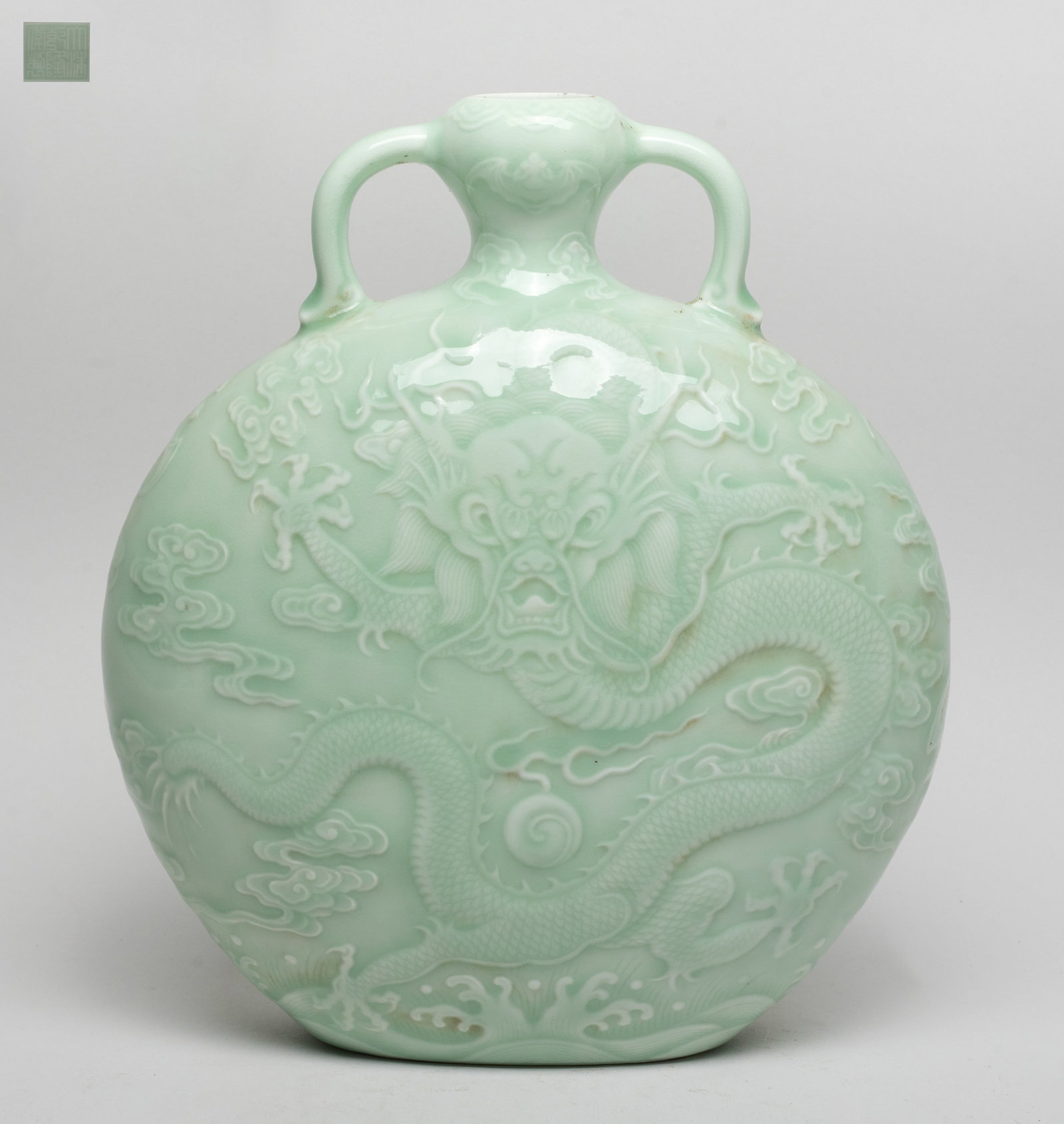Chinese Bean Green Glazed Porcelain Vase: Either side carved in low relief on the body with a ferocious dragon pursuing a flaming pearl amidst clouds above waves, and on the neck with a bat, the exterior covered with soft bean green glaze,