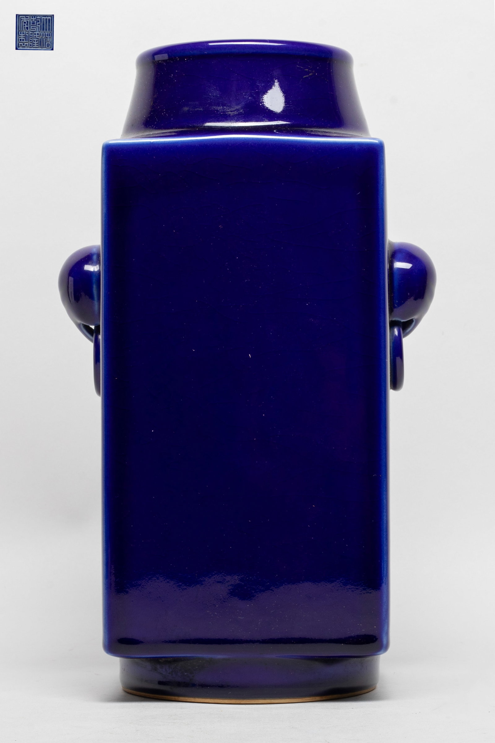 Chinese Rich Blue Glazed Porcelain Vase: The vessel modelled after the archaic jade prototype, of tall square rectangular form, the sides with a pair of elephant-head fixed-ring handles, covered overall except for the foot ring with a deep v