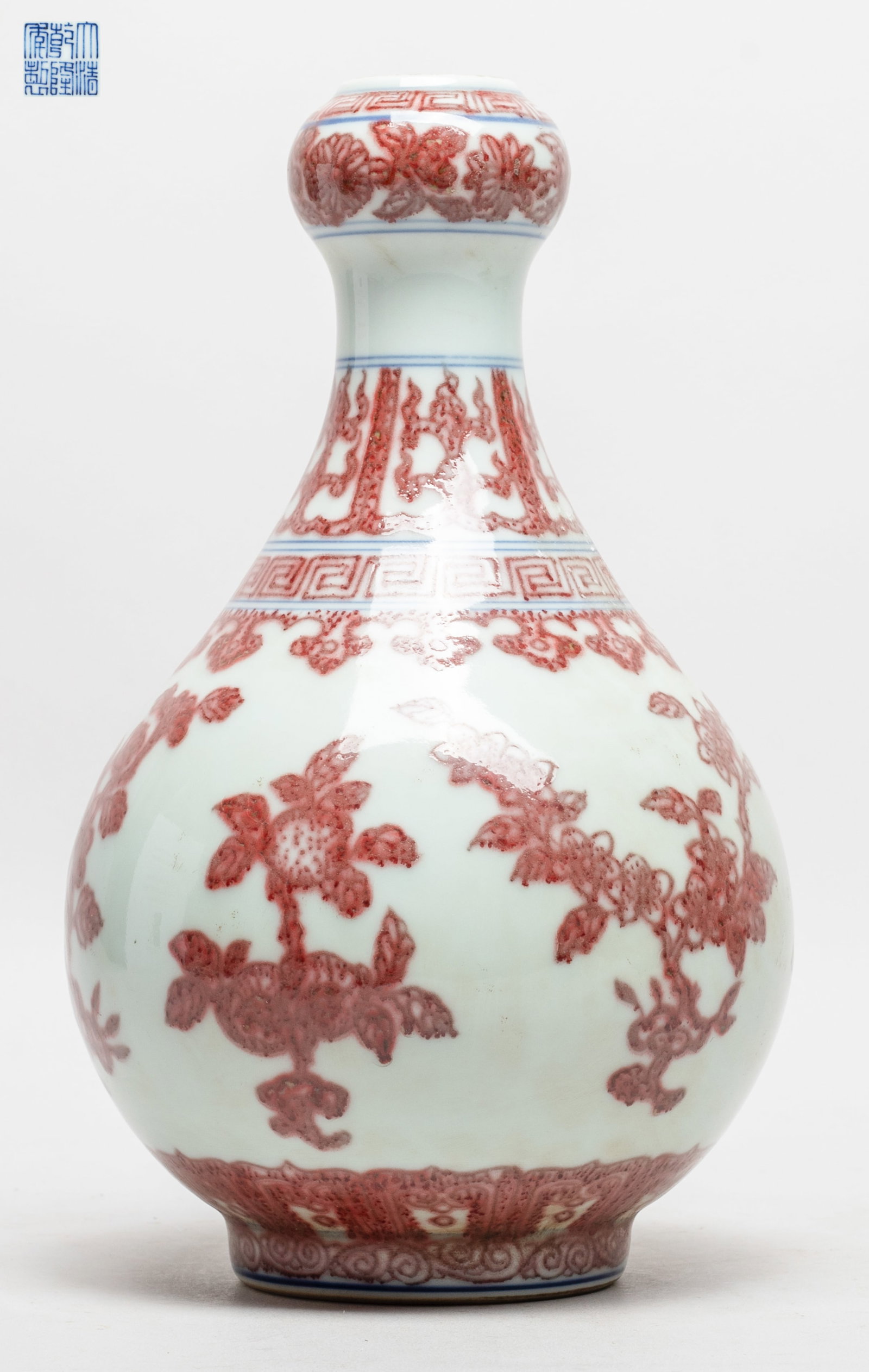 Chinese Copper Red Glazed Porcelain Vase: The pear shaped body rising from a short foot to a waisted neck and a garlic mouth, the exterior painted in copper red with flowers and fruits, under bands of flowers, lappets and ruyi heads, above ba