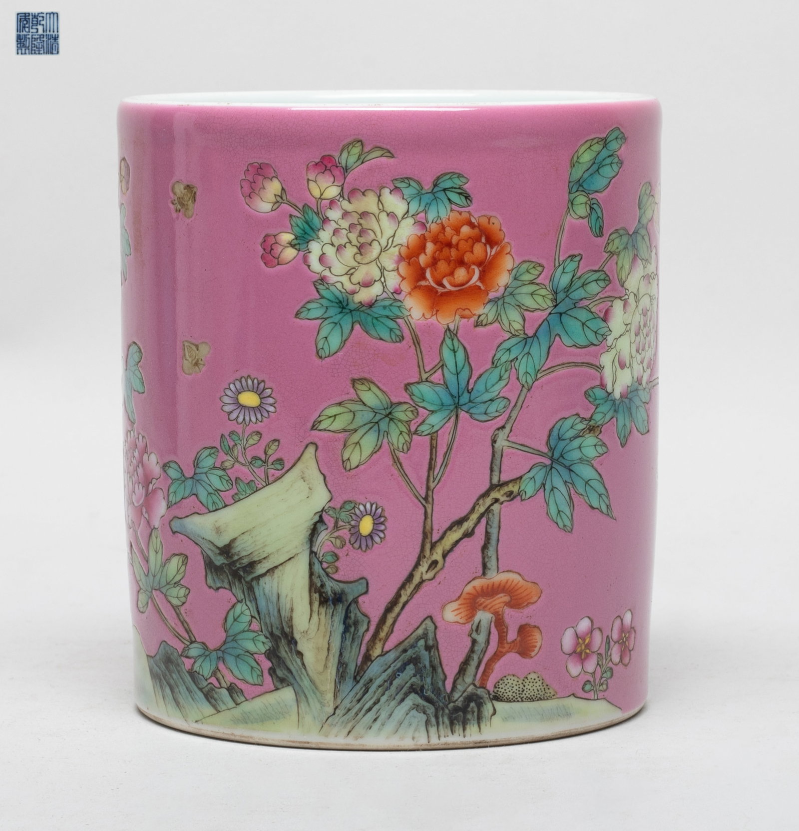 Chinese Export Famille Rose Porcelain Brush Pot: Of cylindrical form, the exterior decorated with peony and lingzhi against rouge-pink glazed body, the bottom with a six-character mark. Approx. 5.3*4.8 inch.
