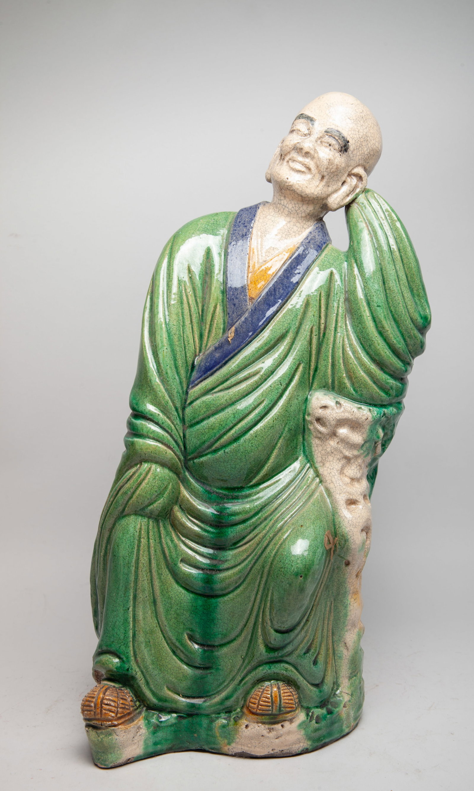 Tall Chinese Vintage Stoneware Figure of Luohan: The seated Luohan wearing a long loose-fitting robe and straw sandals, the bending left arm supporting his head, applied with crackled green blue, brown and creamy glaze. Approx. 19.6*8.5*6 inch.