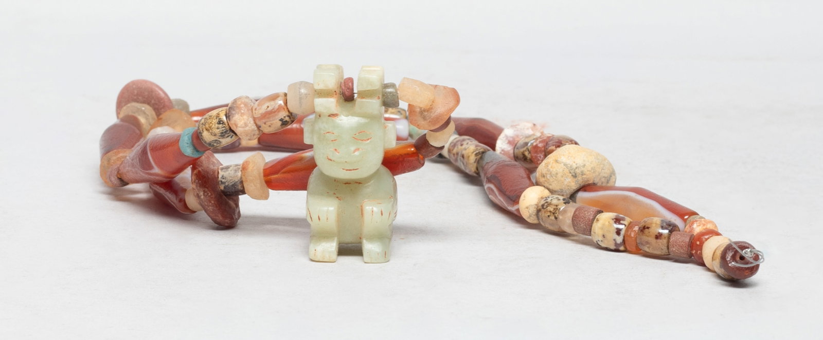 Chinese Jade, Stone & Agate Necklace: Special form Chinese agate and stone bead necklace, with a jade pendant carved as a seated figure. Approx. 26 inch L. The Estate of S Pasadena, CA, 2023.