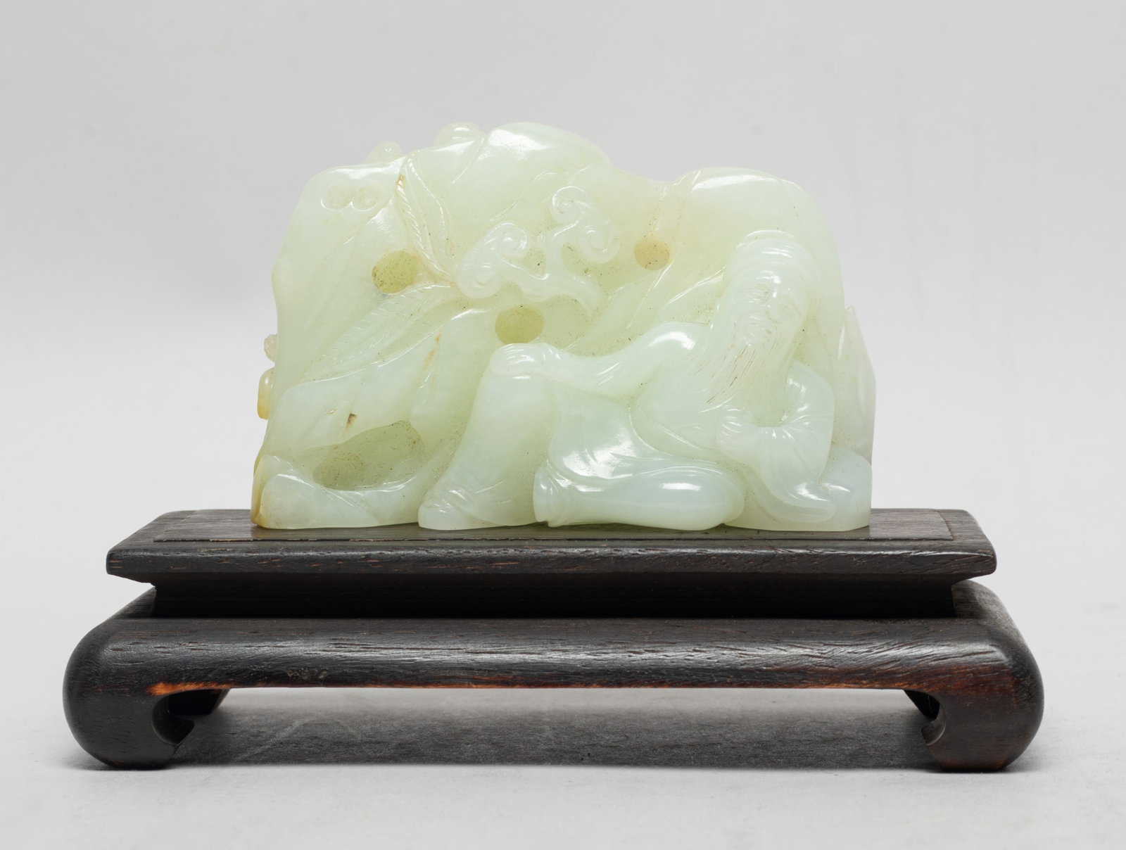Chinese White Jade Sculpture on Wood Base: One side carved figure and lingzhi, the reverse carved chilong and pine tree, with wood base. Approx. 3.6*2.34*1.33 inch (w/o base).