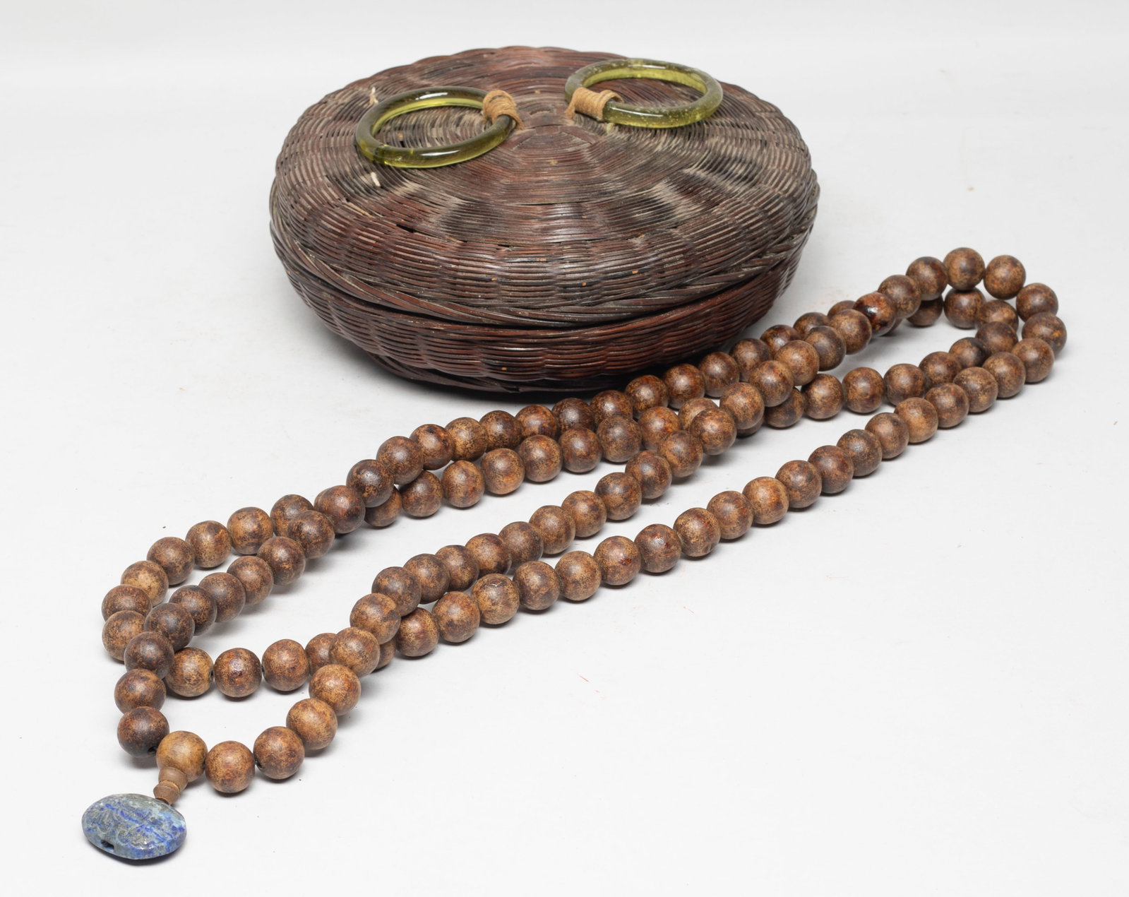 Chinese Agarwood Prayer Beads: Long string of Chinese agarwood carved prayer beads, with a stone pendant carved with bats and shou characters, with a rattan box. Approx. 120 gram (wood bead and stone pendant weight). The Estate of 