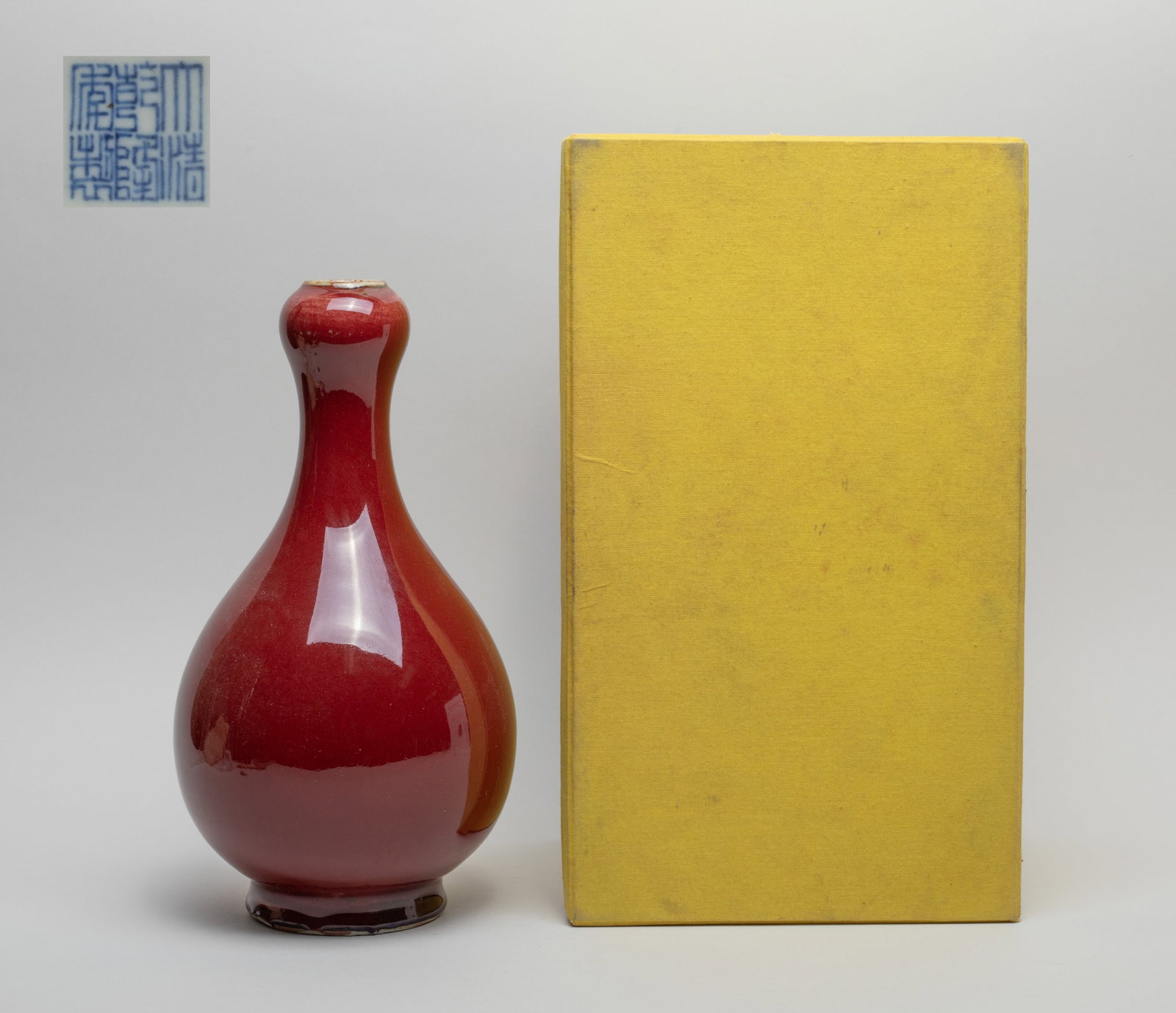 Chinese Red Glazed Porcelain Vase w/ Box: The pear-shaped body rising from a splayed foot to a waisted neck with a garlic mouth, the exterior applied in lustrous crackled red glaze, the bottom inscribed with a six-character mark in underblue 