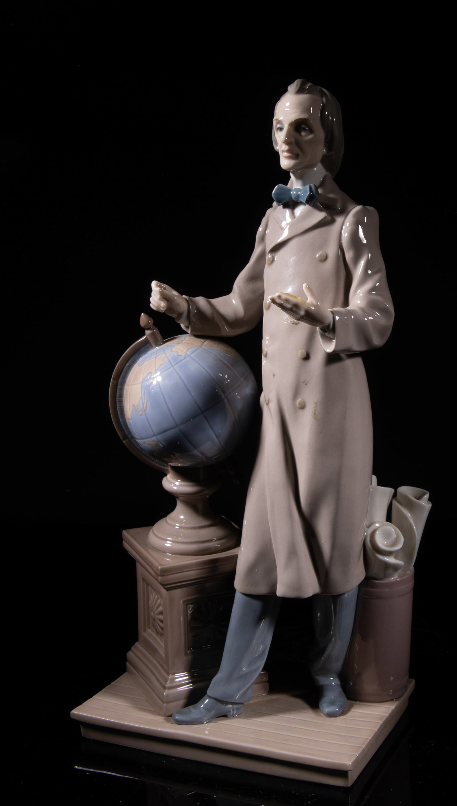 Vintage Tall Lladro Porcelain Sculpture: Molded as a man standing next to a globe and a basket of maps, the bottom marked LLADRP HAND MADE IN SPAIN DAISA. Approx. 13.1*6.1*4 inch. The Estate of the Matte & Son, Palm Springs, 2021.