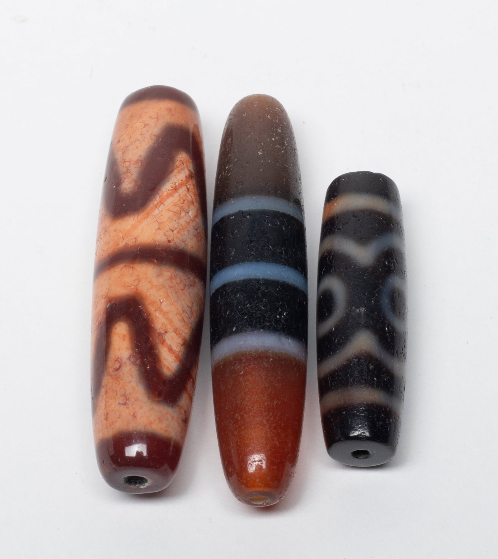 Three Chinese Sino-Tibetan Dzi Beads: Three Chinese Sino-Tibetan dzi beads. Approx. 2.3 inch L (longest).