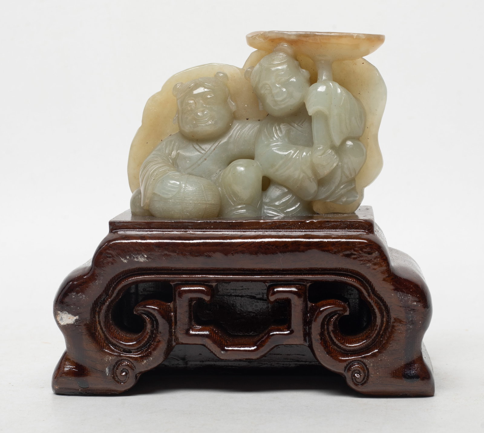 Chinese Russet Jade Figure of Hehe: Chinese russet jade sculpture carved as Hehe Erxian, one figure holding box and the other holding lotus, affixed to stand. Approx. 4.5*4.6*2.3 inch (w/ stand). The Estate of the K. T. Lam. HK. 1998.