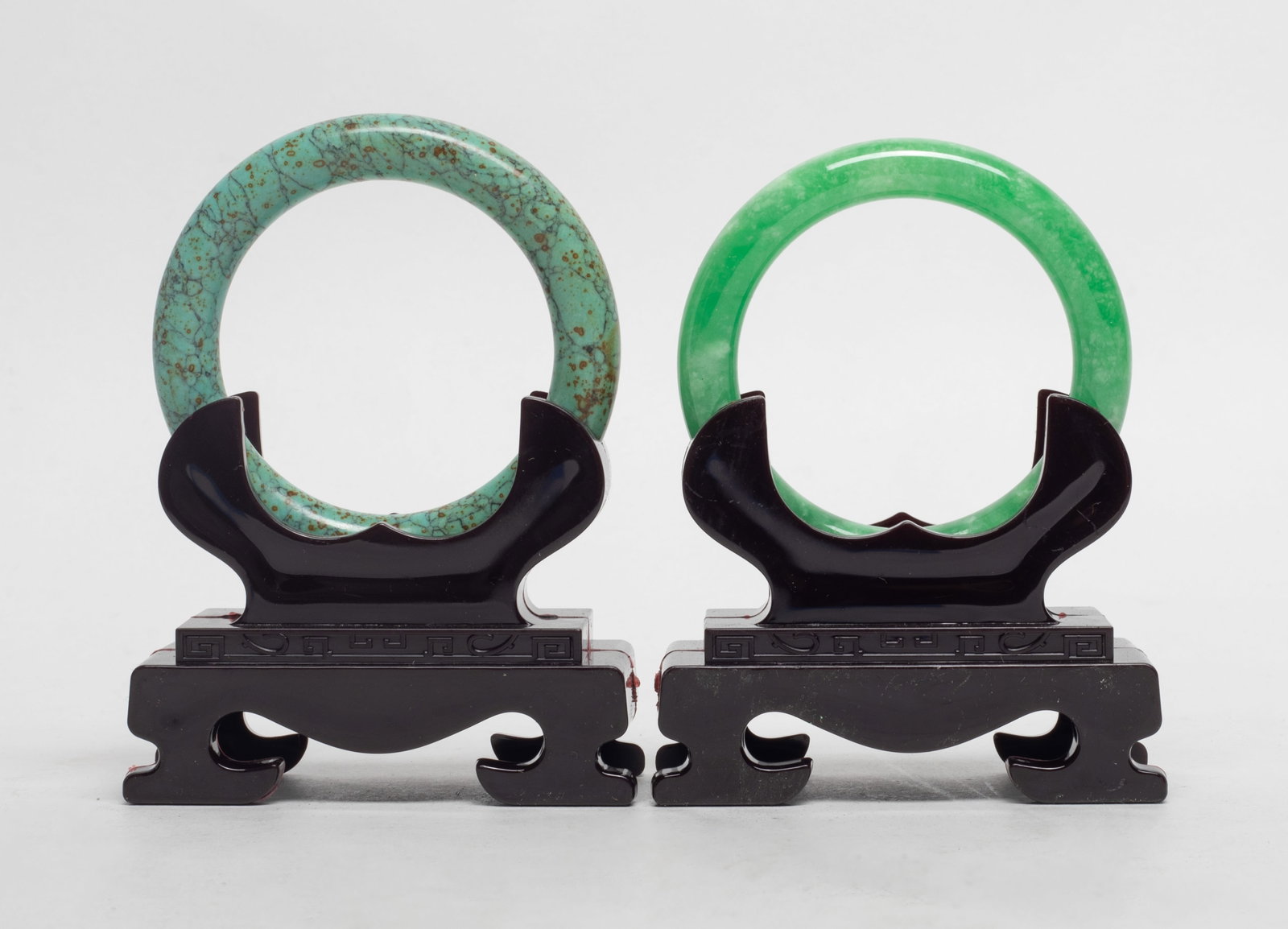 Estate Two Chinese Stone Bangles: Two Chinese stone bangles, with stands. Approx. 3.3 inch outer diameter, 2.35 inch inner diameter (larger).