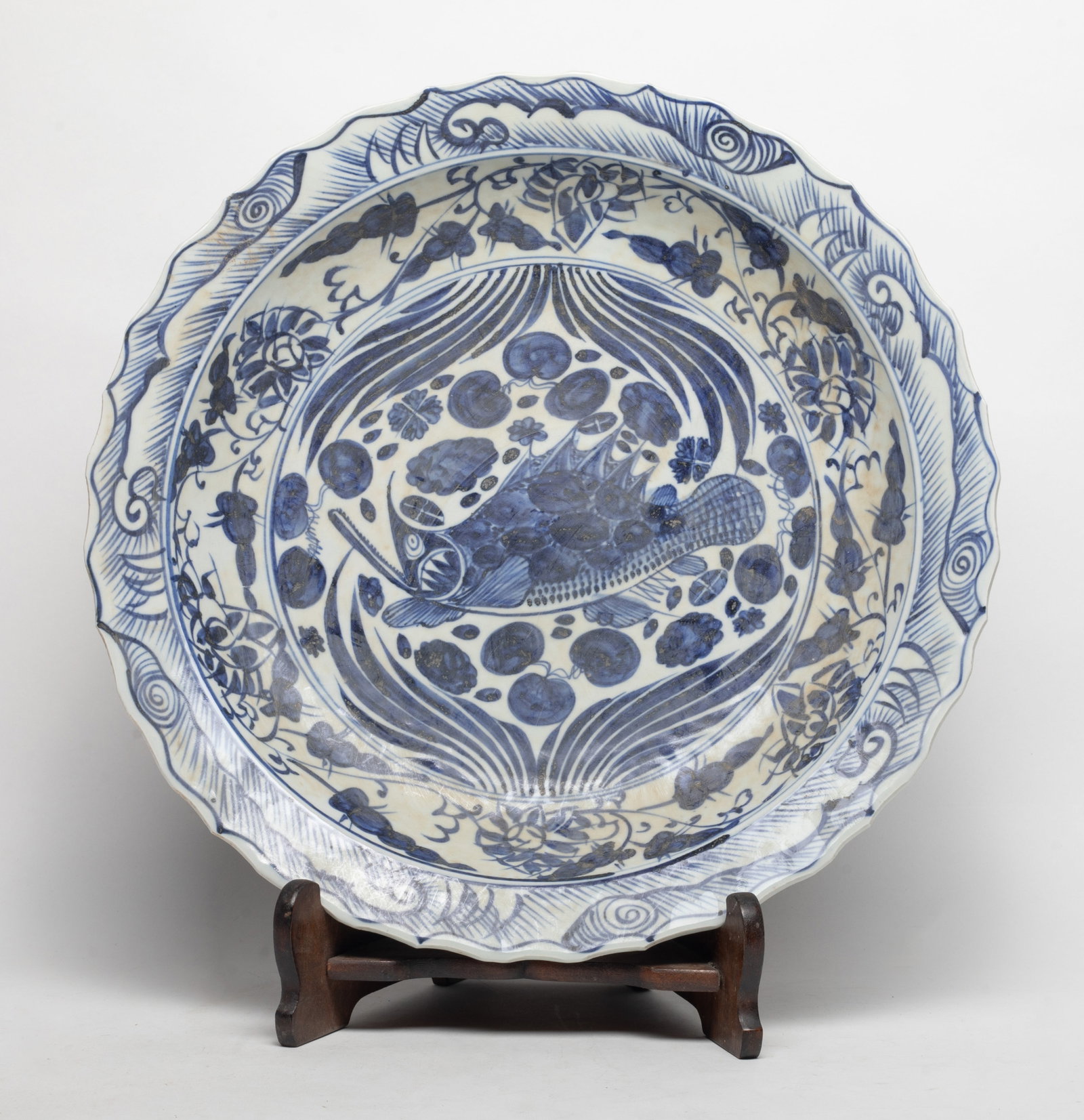 Large Chinese Blue White Porcelain Plate: Large Chinese blue and white porcelain plated, the interior painted with fish amidst aquatic weeds, with a wood display stand. Approx. 15.8*2.2 inch
