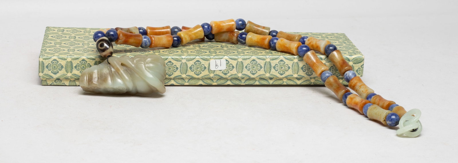 Chinese Export Long Jade Necklace: Chinese russet jade bead and blue gemstone bead necklace, suspended with an agate bead and a jade pendant carved as two lotus seedpods issuing from a short stem, with box. Approx. 2.6*1.2*0.9 inch