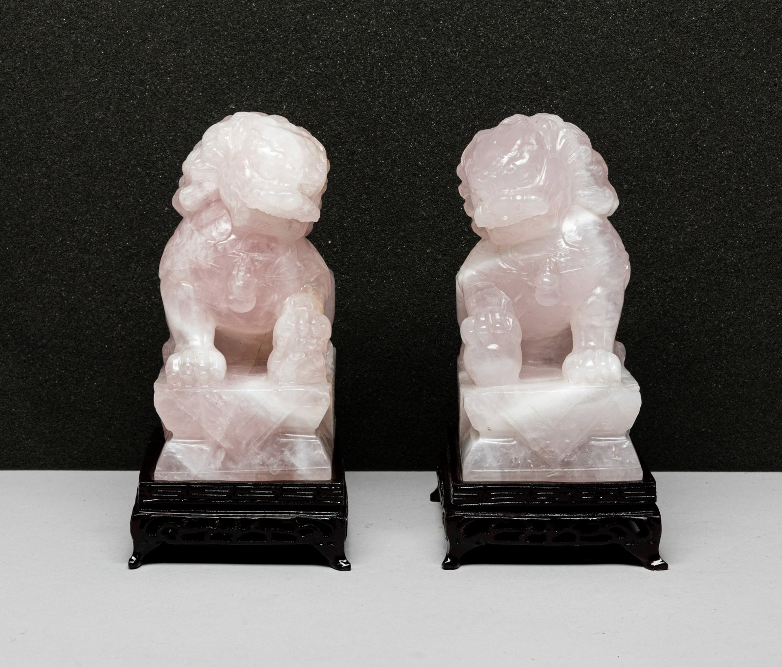 Two Chinese Rose Quartz Foo-dogs: A pair of Chinese rose quartz Foo-dogs, with fitted wood stand. . Approx. 3.0*4.0*6.2 inches (W/O stand). The Estate of the Los Angeles Store Closed Sale.