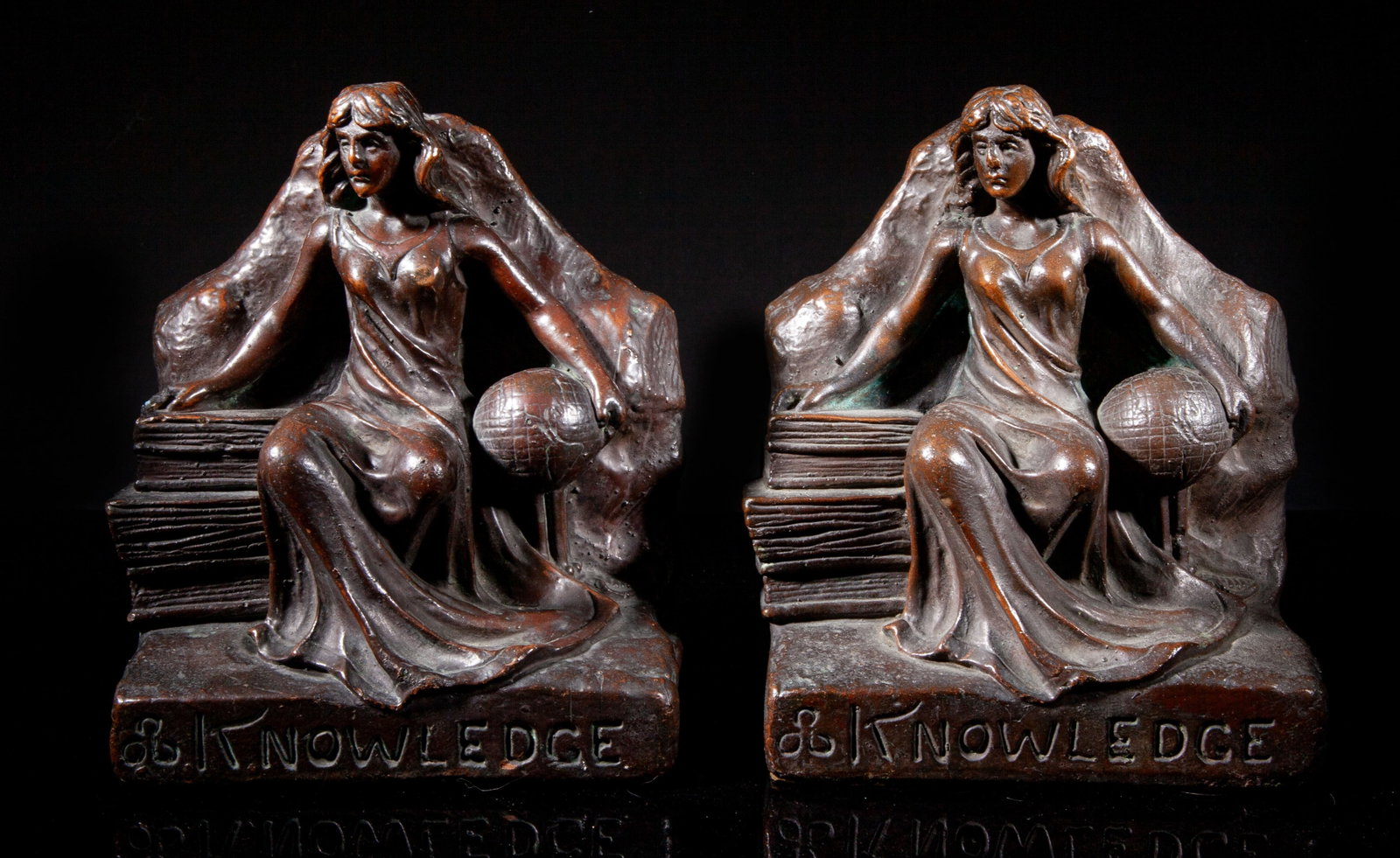 Antique Early 1900s Bronze Sculptures Bookends: Pair of antique bronze bookend sculptures, each cast with a woman sitting between books and globe, wearing a long flowing robe, marked KNOWLEDGE. Approx. 8.2*7.1*4.2 inch (each). The Estate of the Hun