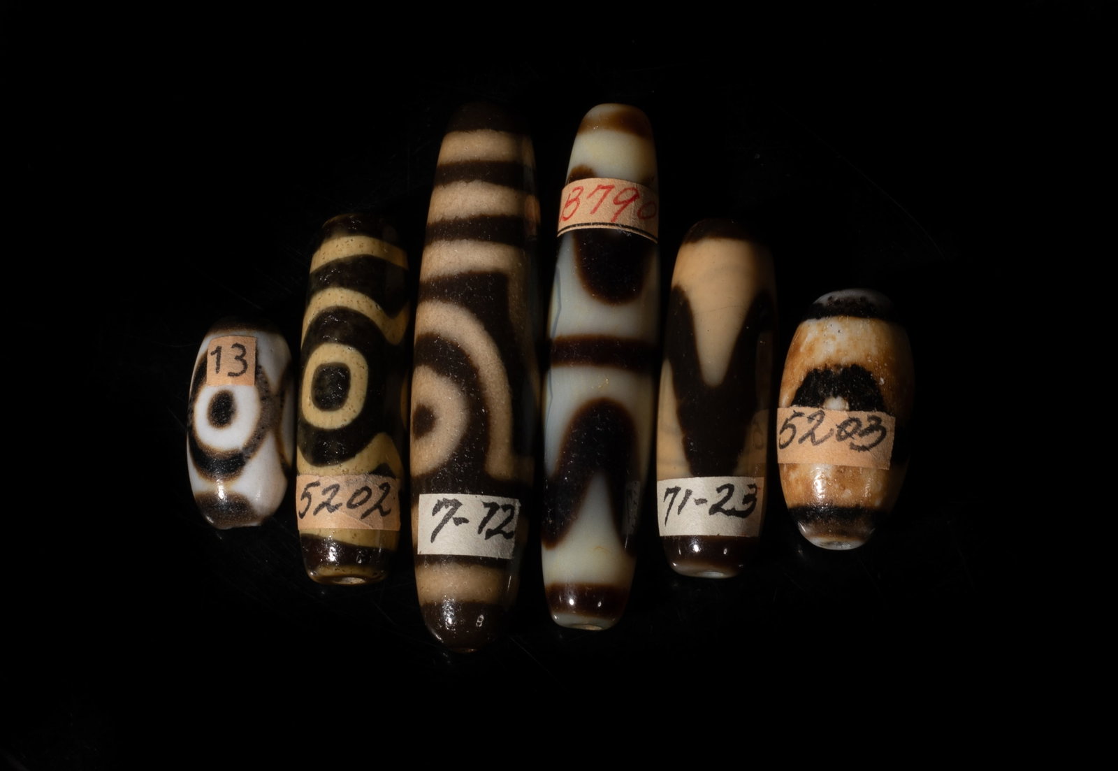 Set Chinese Export Dzi Beads Collection: Set of six Chinese dzi beads. Approx. 2.25 inch L (longest). The Estate of the Pi Sum Park. Newport Beach. 1995.
